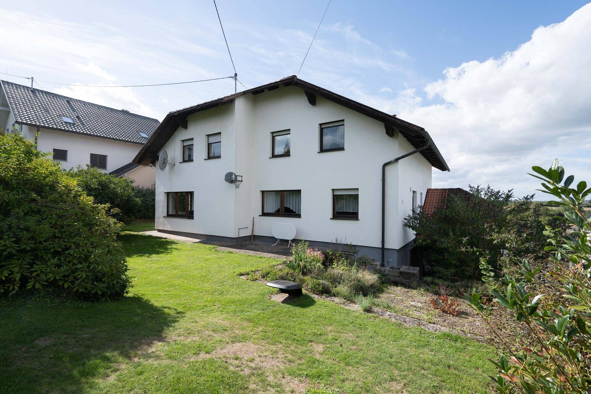 Rückansicht des Hauses mit grünem Rasen und Blick auf die umliegende Landschaft.