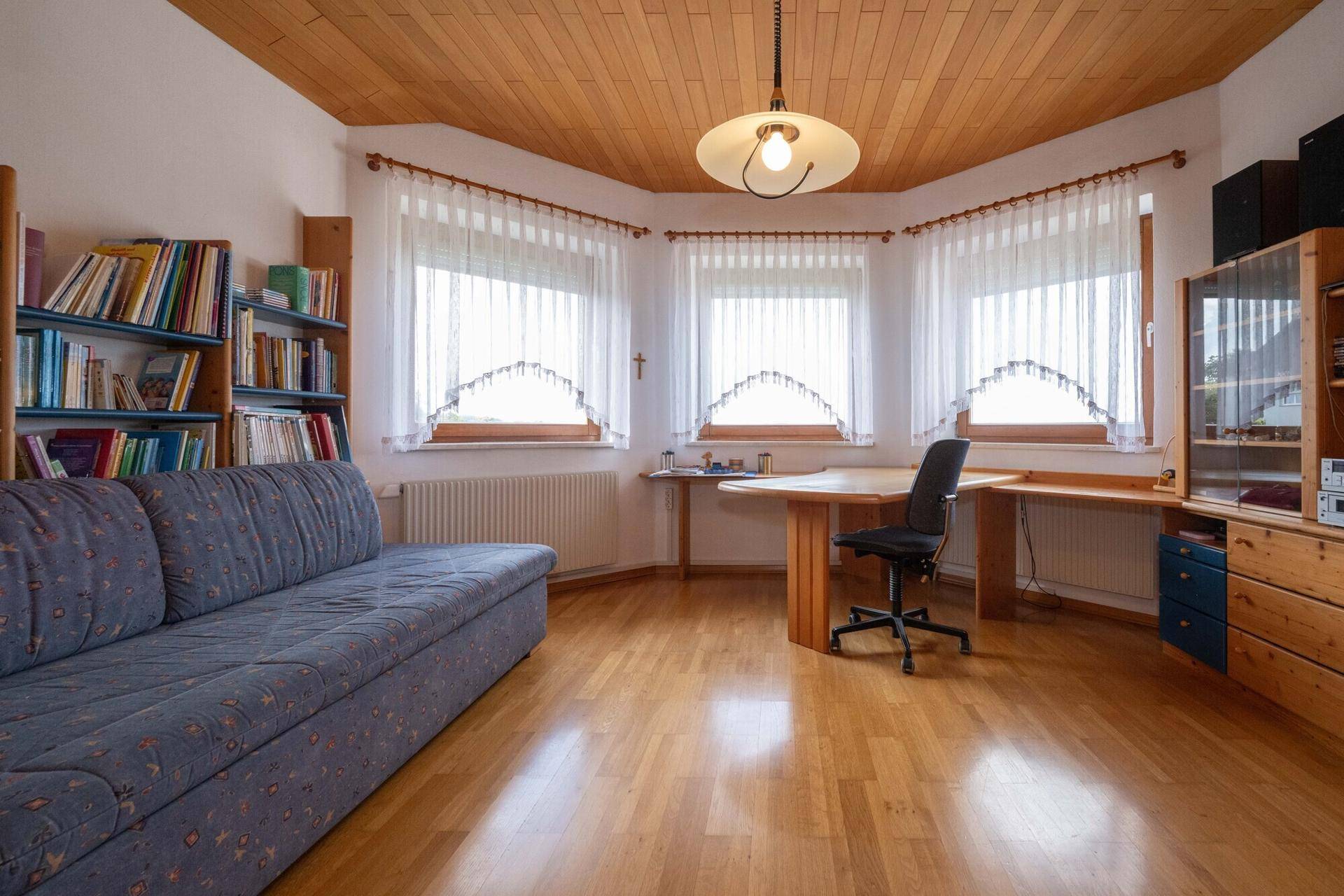 Helles Arbeitszimmer mit Holzdecke, Schreibtisch und Bücherregalen, ideal für Home-Office.