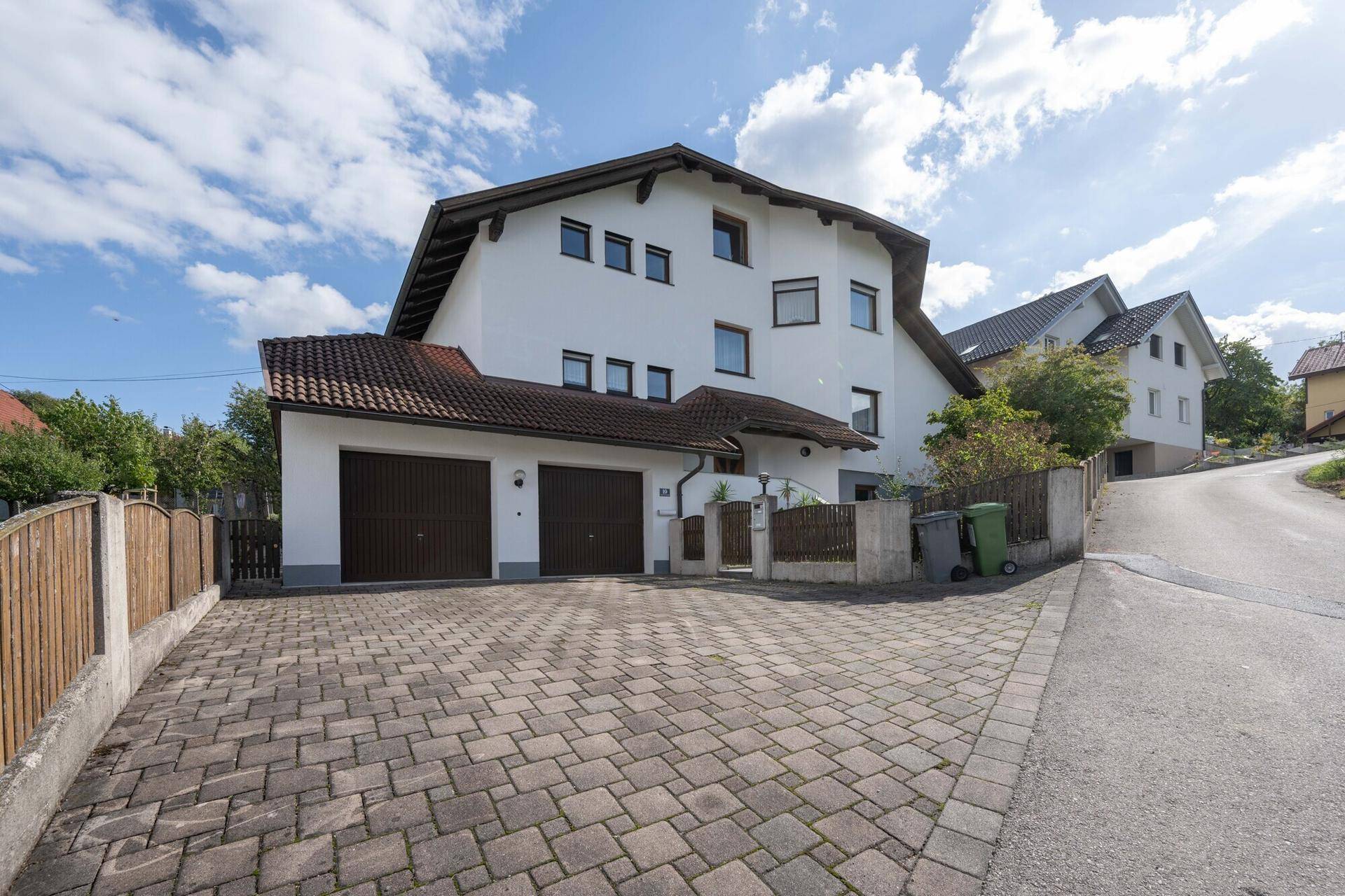 Ansicht des Einfamilienhauses von der Straße mit gepflasterter Auffahrt und Doppelgarage.