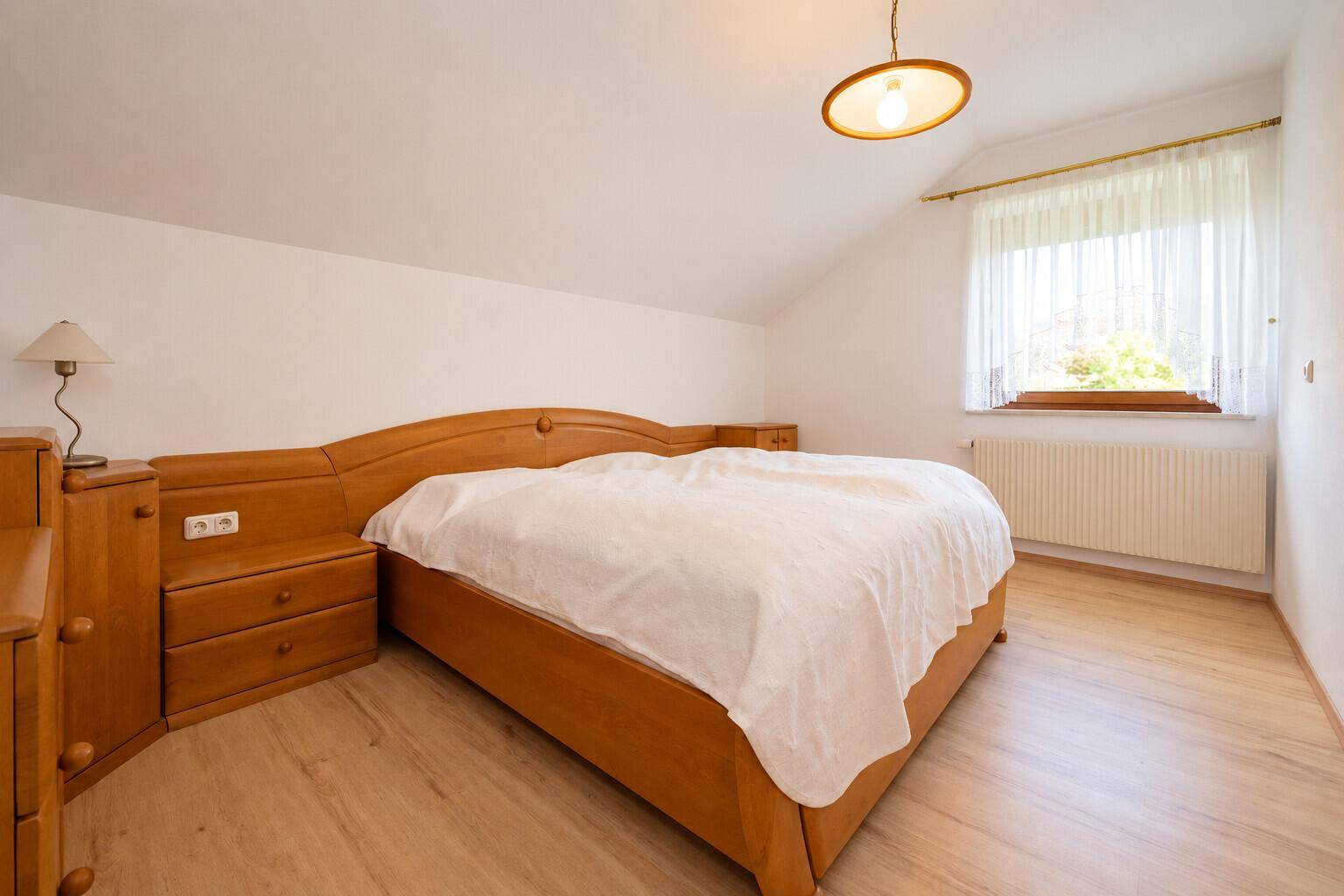 Gemütliches Schlafzimmer mit Holzmöbeln und Dachschräge, bietet eine ruhige Atmosphäre.