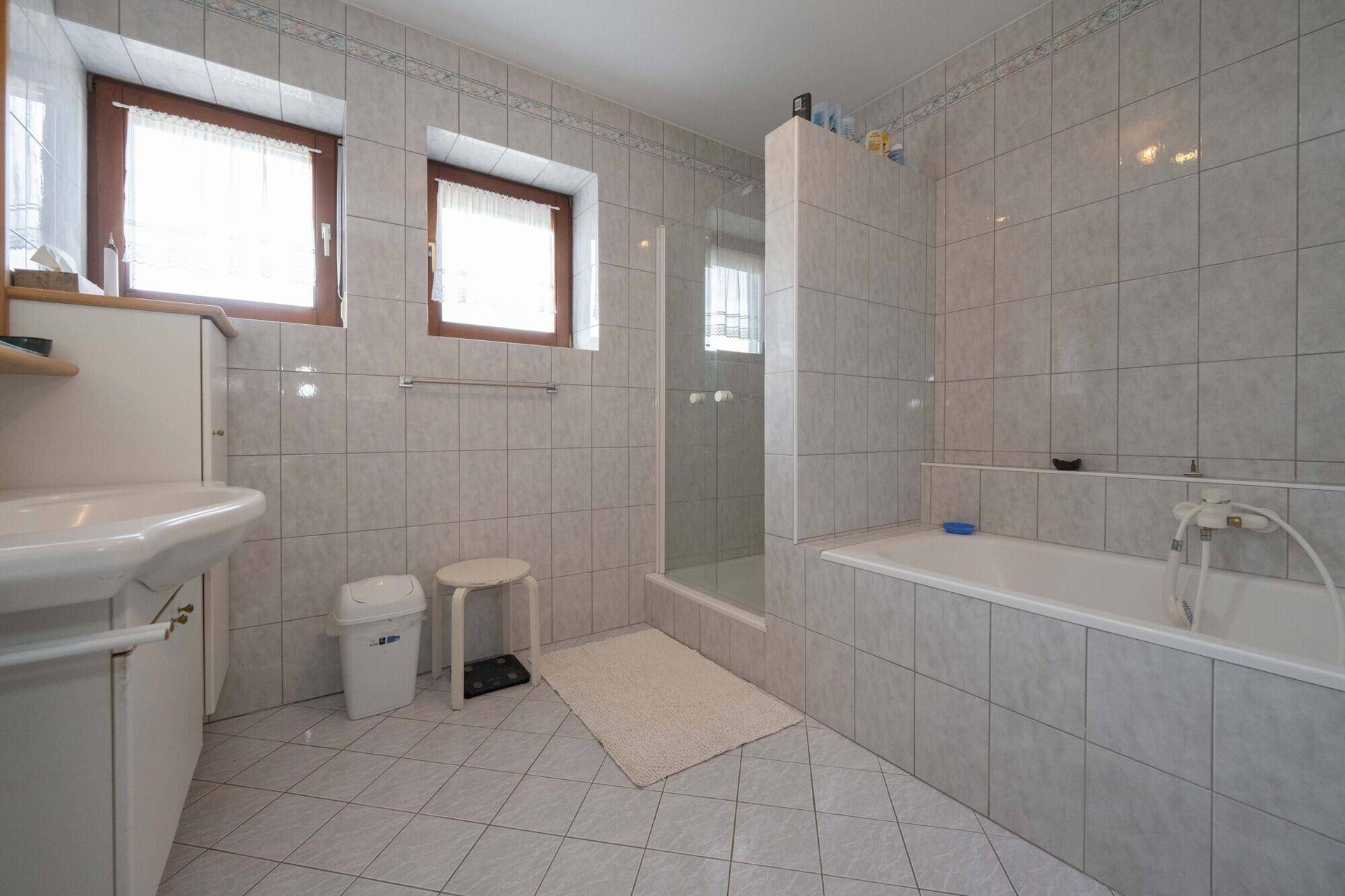 Badezimmer mit hellen Fliesen, Badewanne und separater Duschkabine.