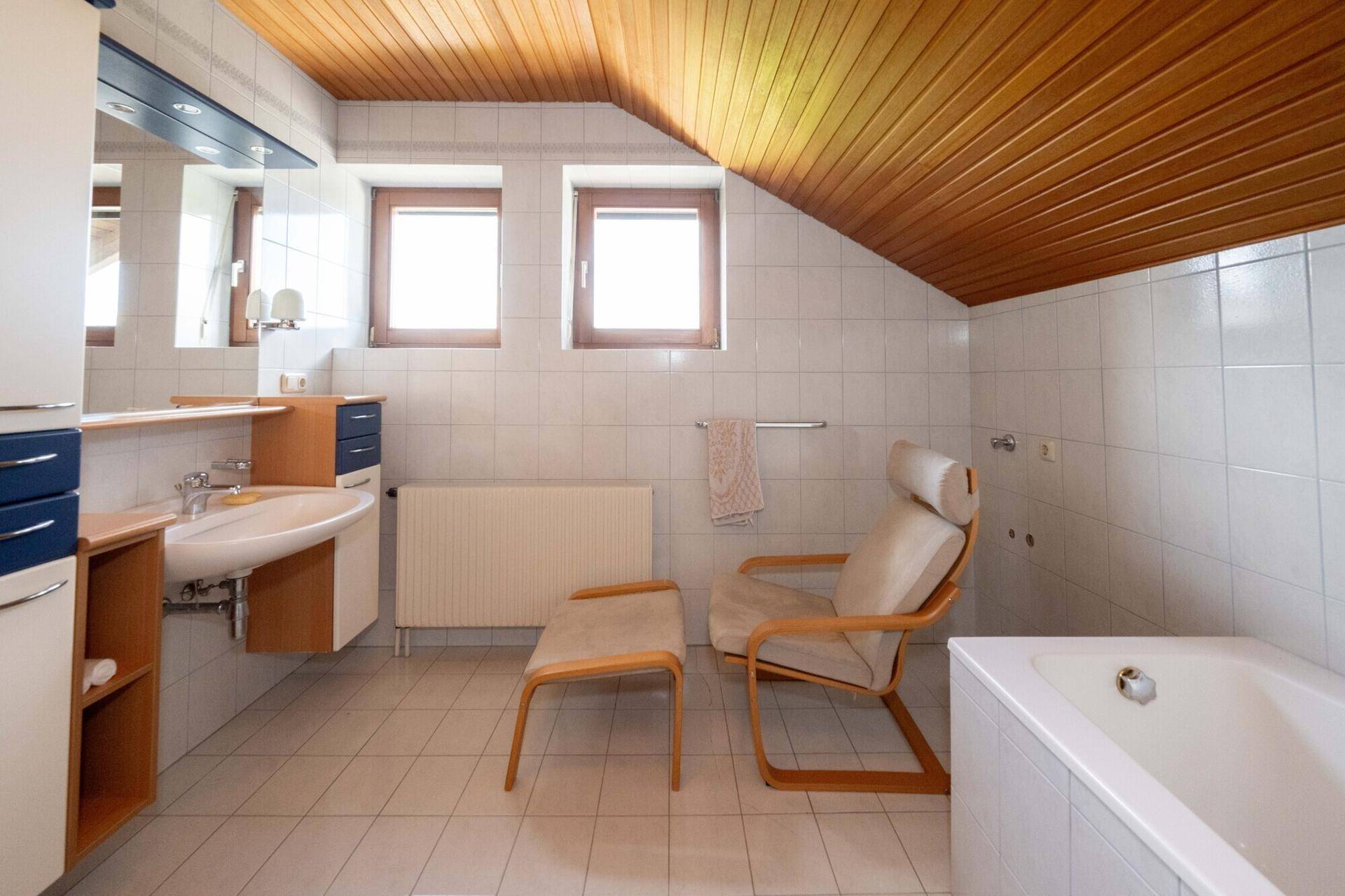 Badezimmer mit Badewanne, Holzdecke und Dachschräge, bietet eine entspannende Atmosphäre.