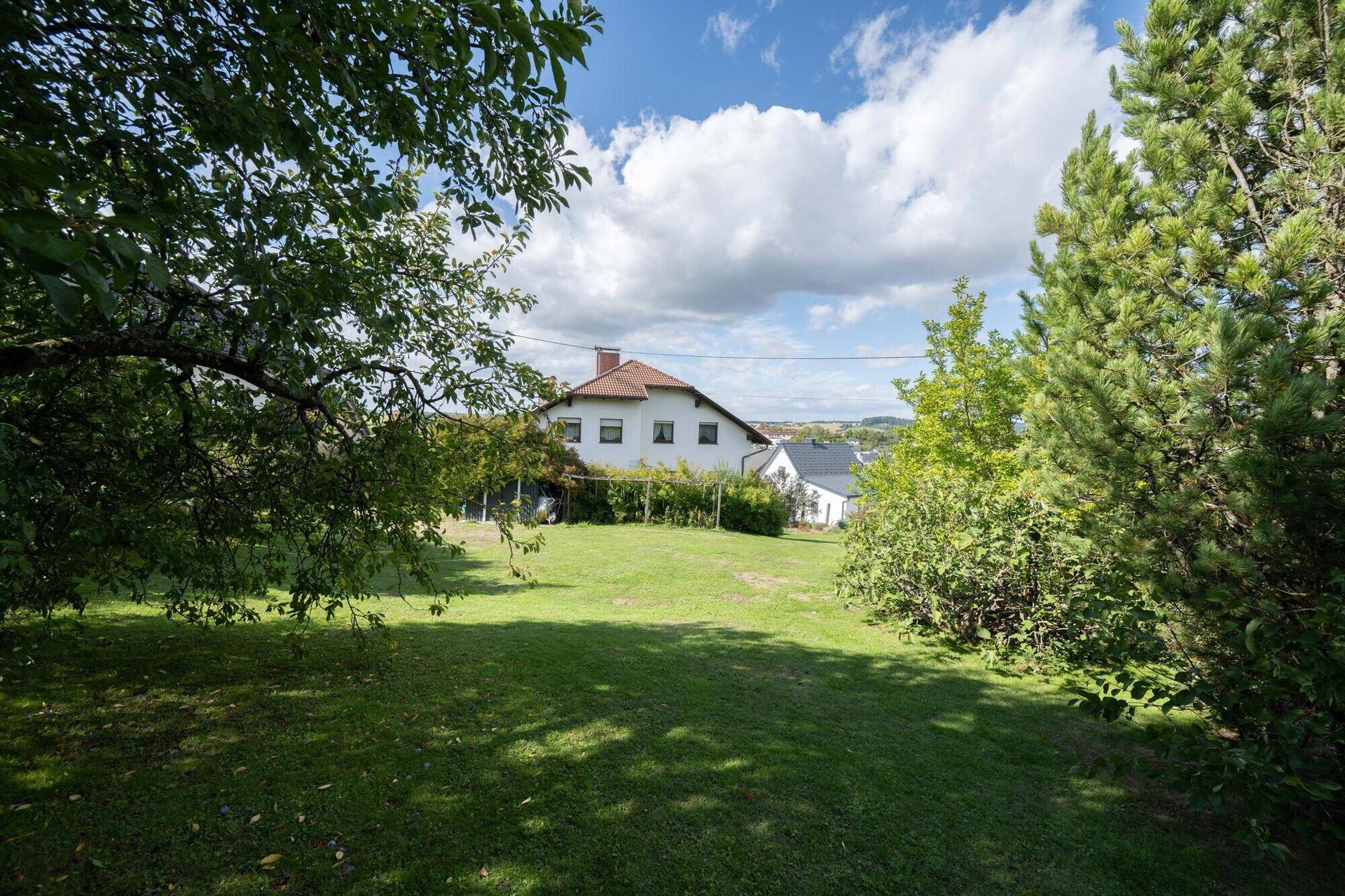 Weitläufiger Garten mit Rasenfläche und Blick auf das Haus im Hintergrund.
