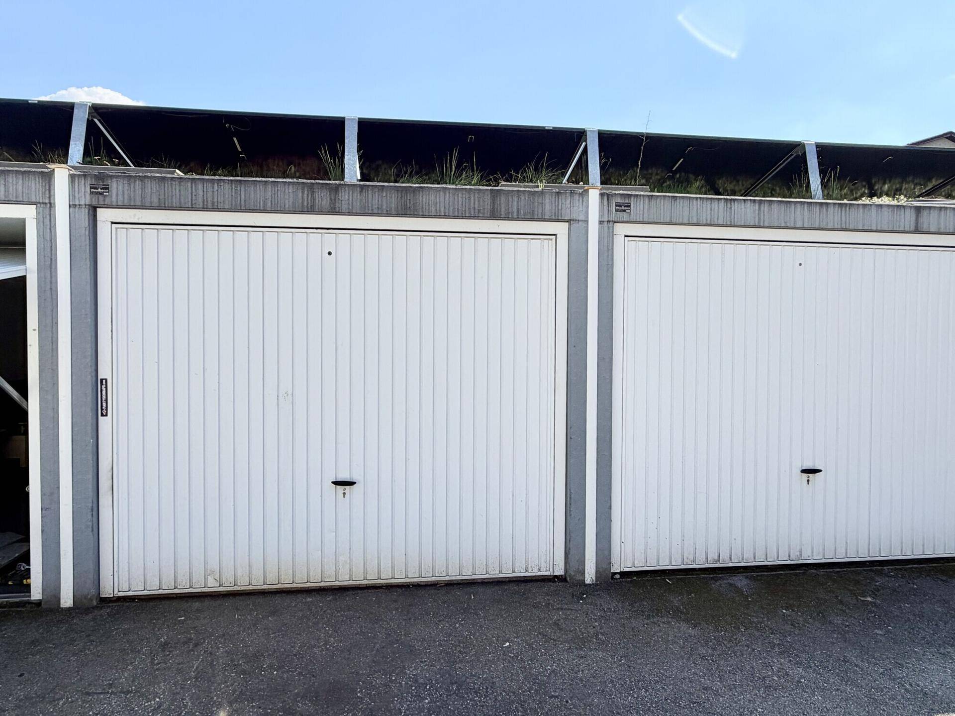 Nahaufnahme von zwei weißen Garagentoren mit vertikalen Lamellen und grauen Rahmen.