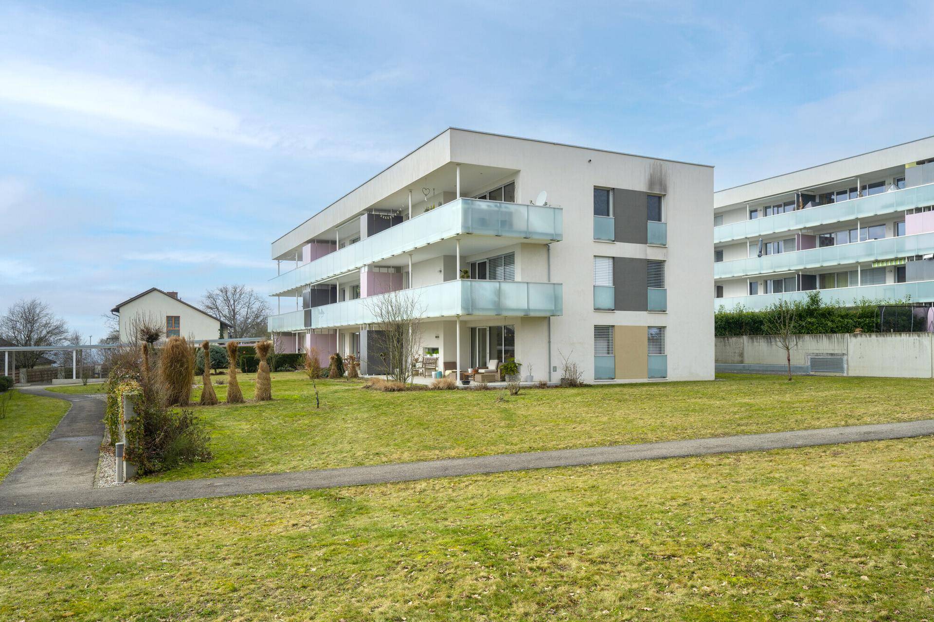 Außenansicht eines modernen Wohngebäudes mit Balkonen und weitläufigen Grünflächen.