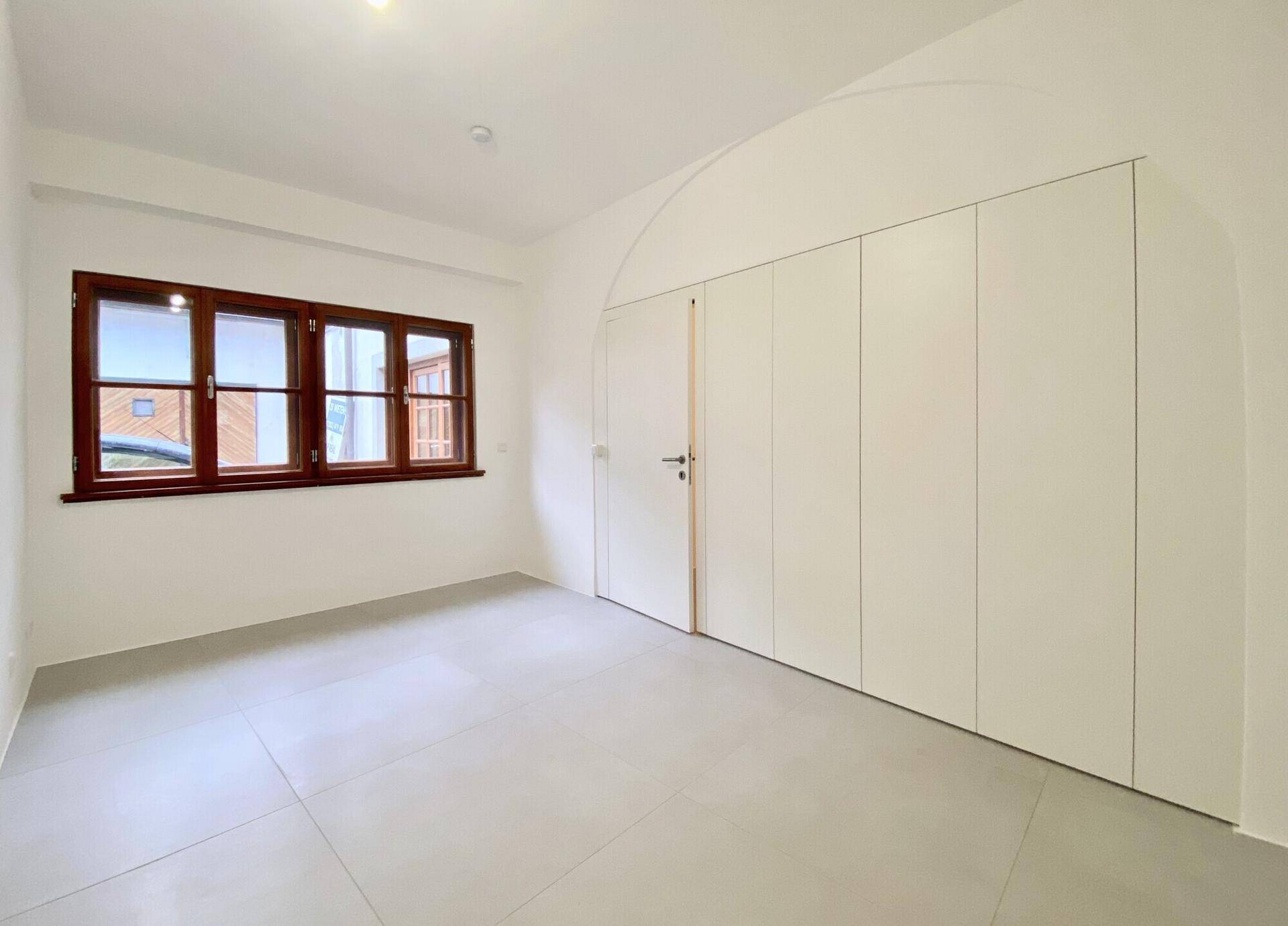 Helles Schlafzimmer mit Einbauschränken, großen Fenstern und modernen Fliesenböden.