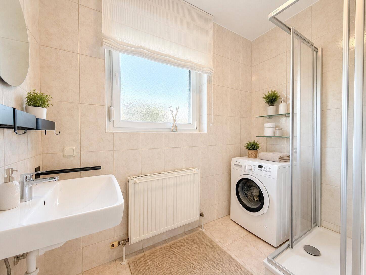 Modernes Badezimmer mit Dusche, Waschbecken, Waschmaschine und Fenster für Tageslicht.