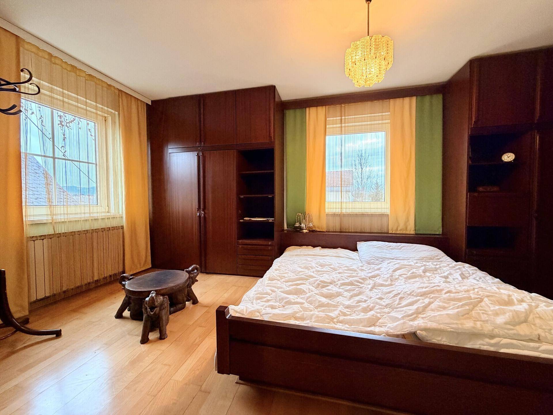 Schlafzimmer mit Doppelbett, Einbauschränken und hellen Vorhängen für viel Tageslicht.
