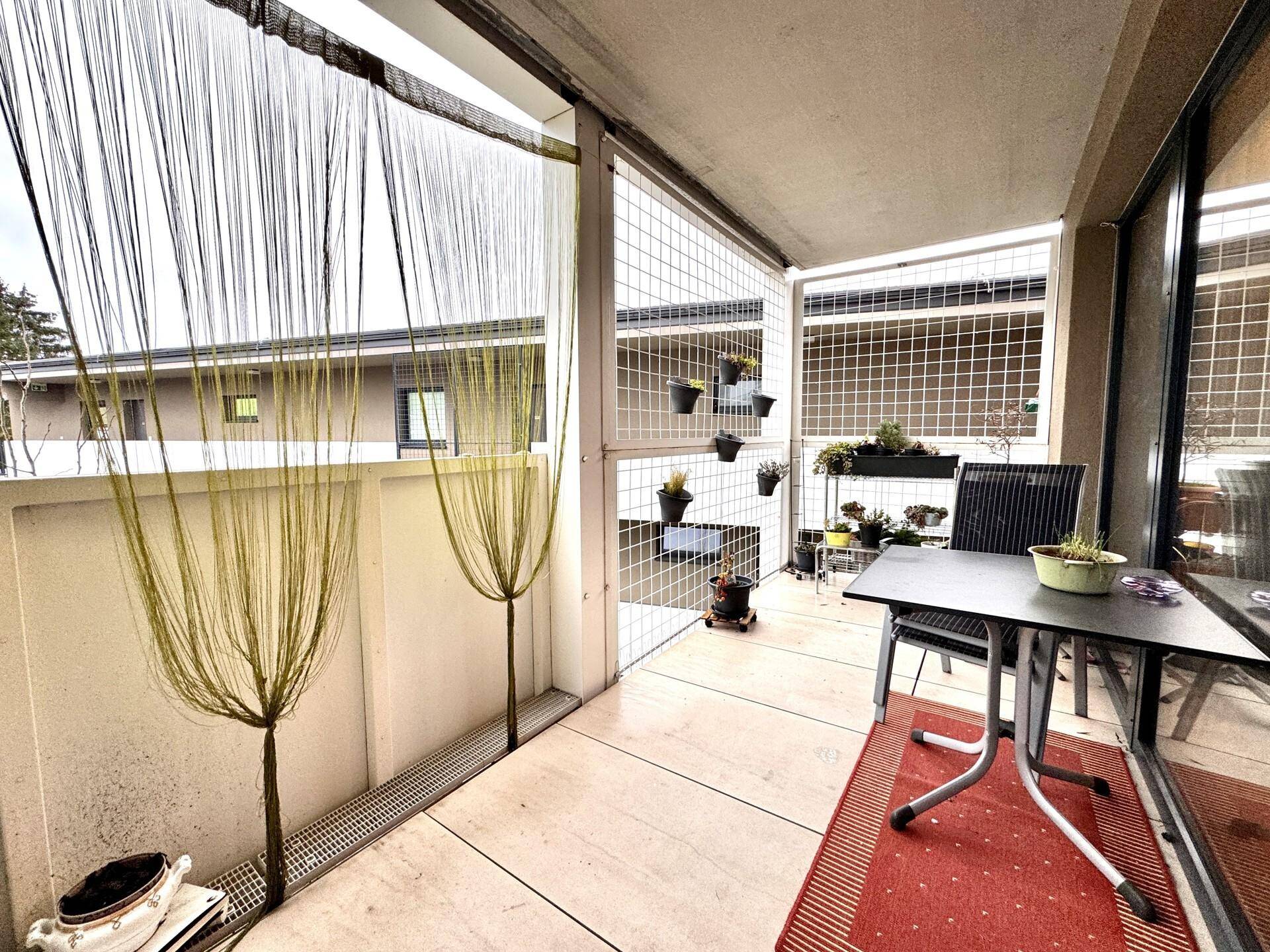 Überdachter Balkon mit Sitzgelegenheiten und Pflanzen, ideal für entspannte Stunden im Freien.