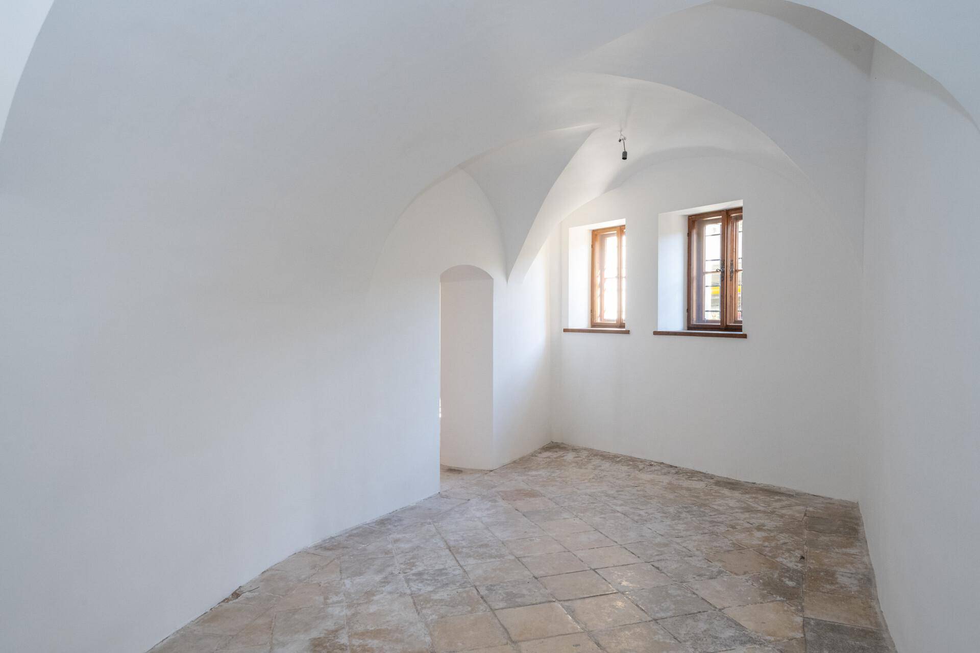 Raum mit gewölbter Decke und zwei Fenstern, der auf die Fertigstellung wartet.