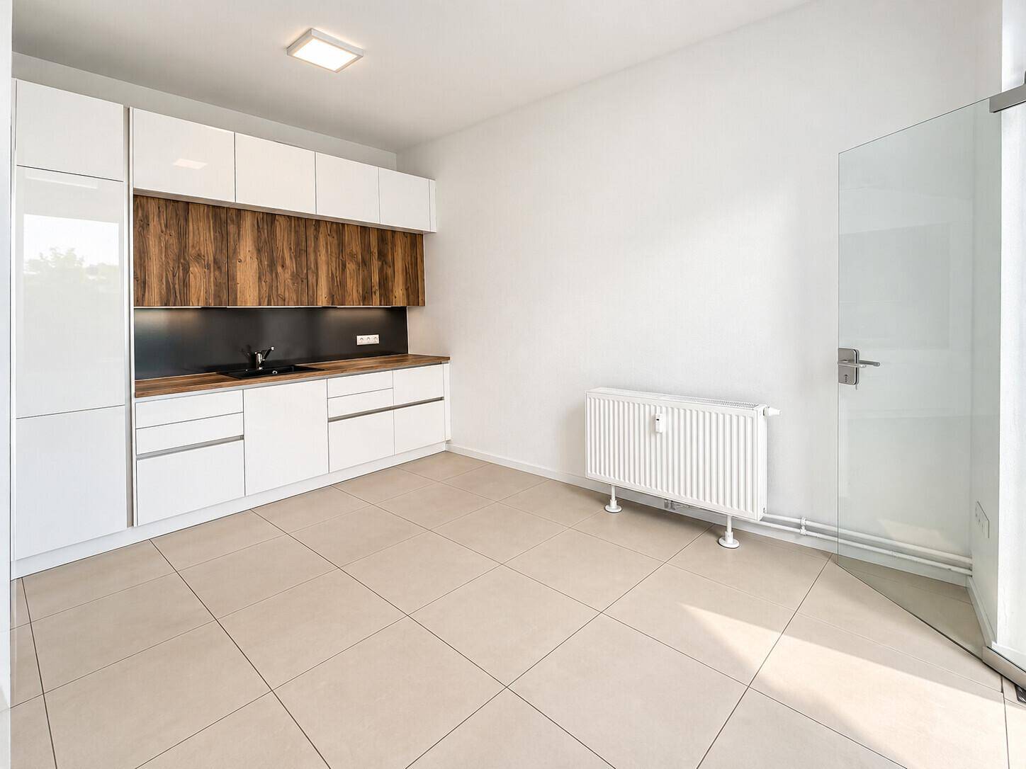 Helle Küchenzeile mit weißen Schränken und dunkler Arbeitsplatte, ideal für ein kleines Büro oder Apartment.
