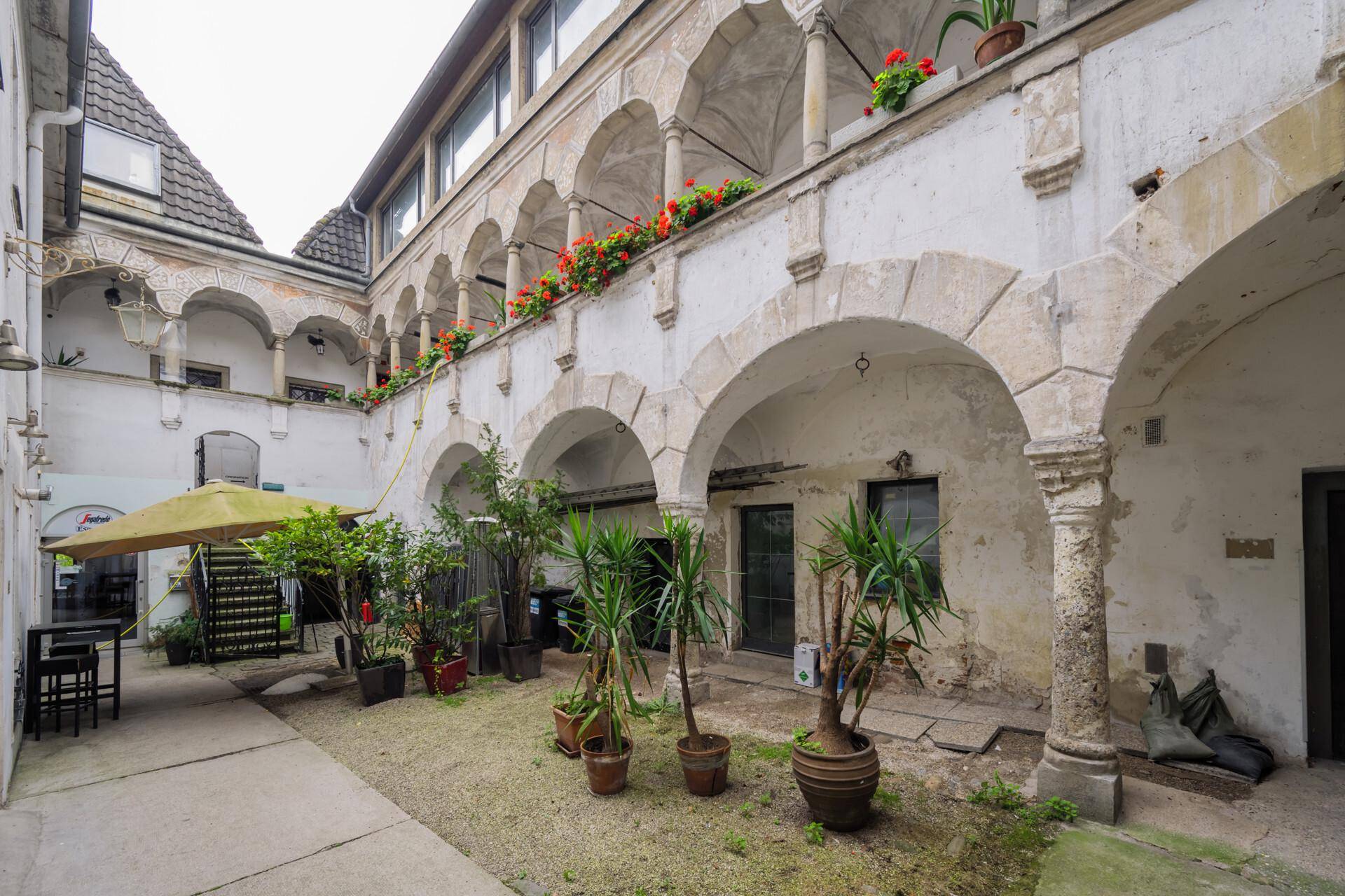 Geräumiger Innenhof mit Arkaden, Pflanzen und einem Sonnenschirm, ideal für entspannte Stunden.