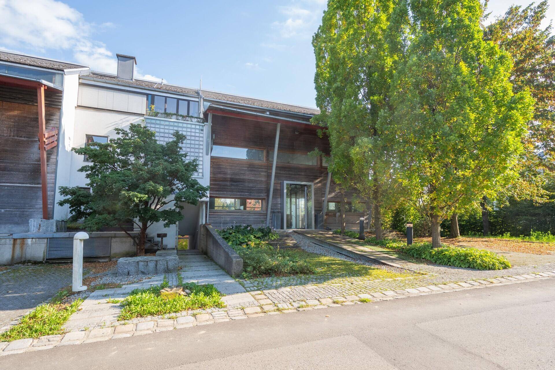 Gesamtansicht des Gebäudes von der Straße mit moderner Holzfassade und Zugangsbereich.