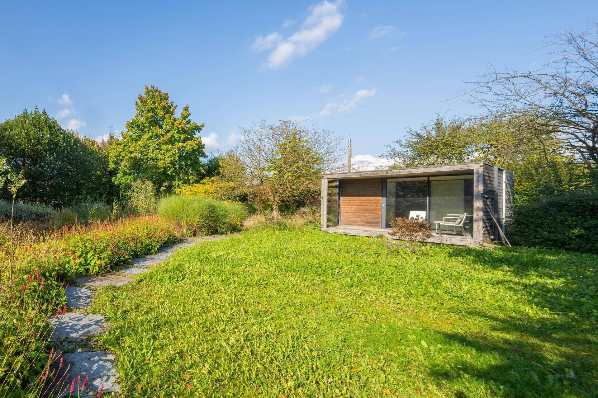 Gepflegte Rasenfläche mit einem modernen Gartenhaus und umgebender Natur.