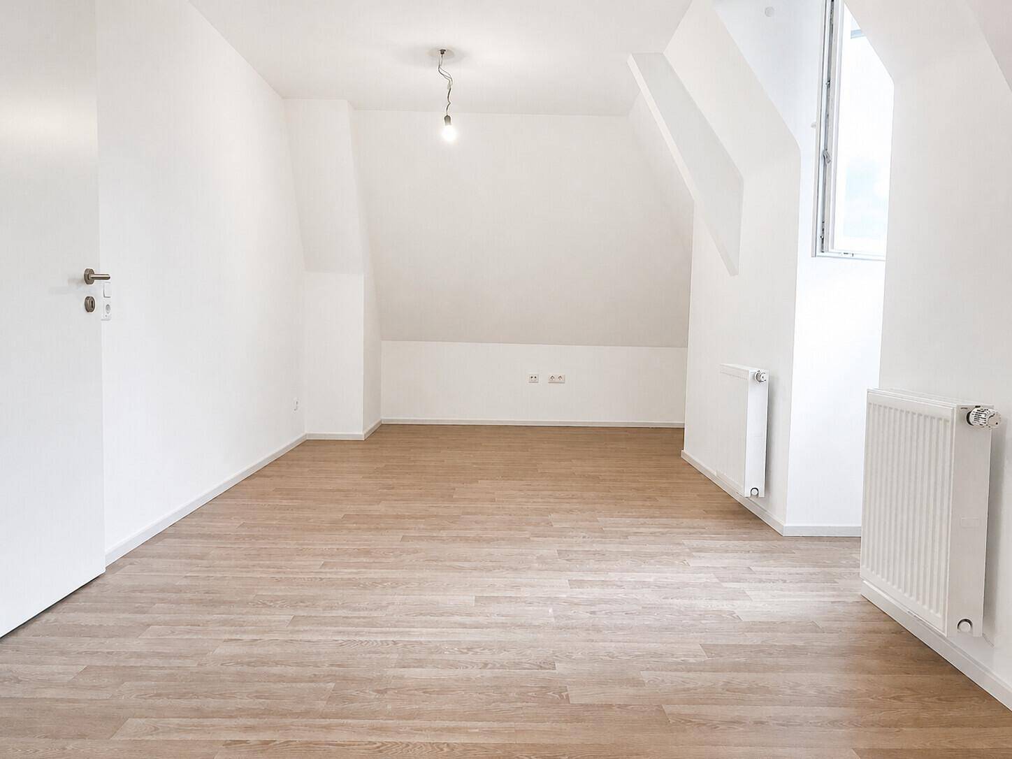 Geräumiger, heller Raum mit Laminatboden und Dachschrägen, bereit für individuelle Gestaltung.