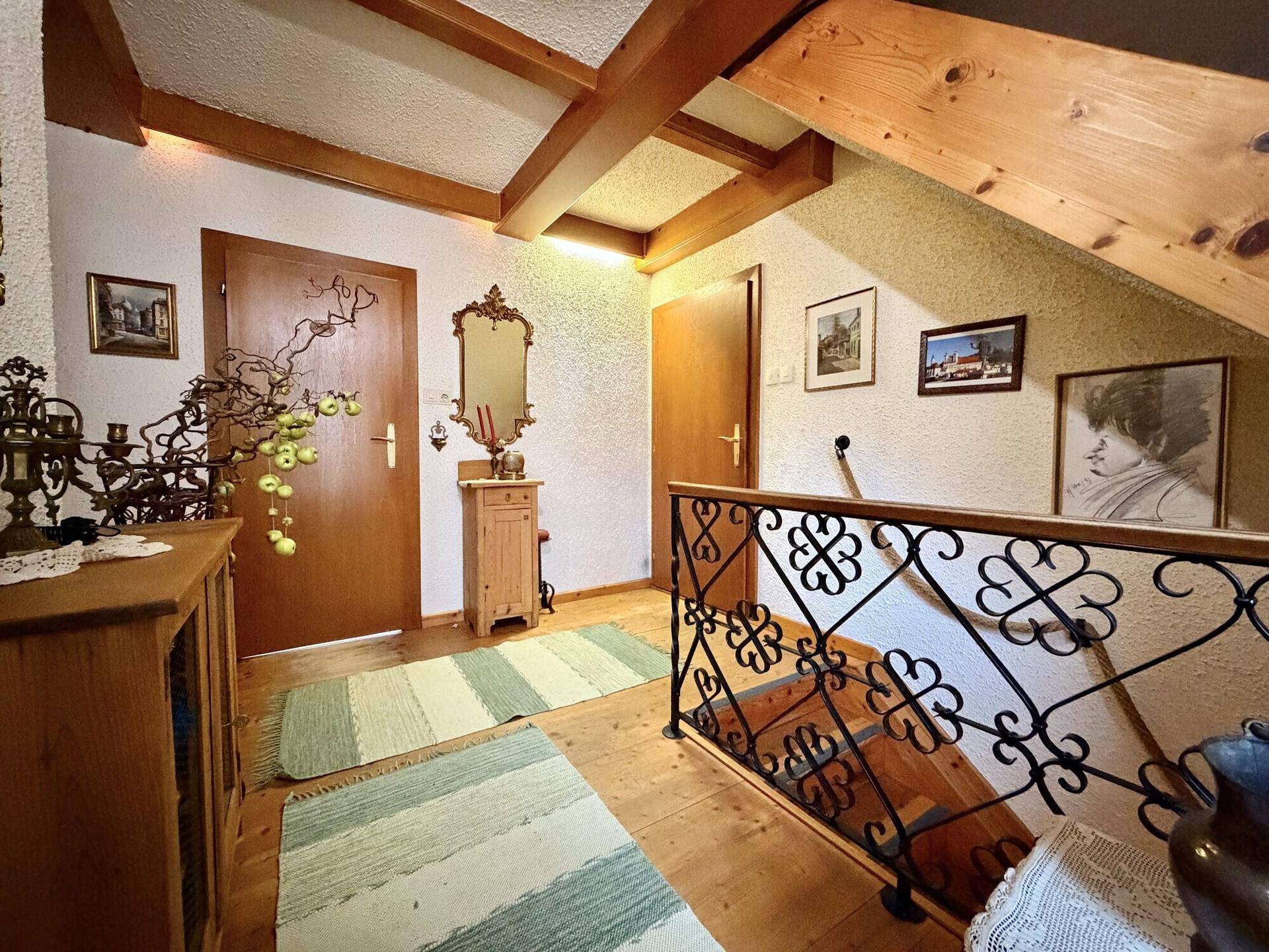 Geräumiger Flur mit Holztreppe, schmiedeeisernem Geländer und rustikalen Dekorationen.