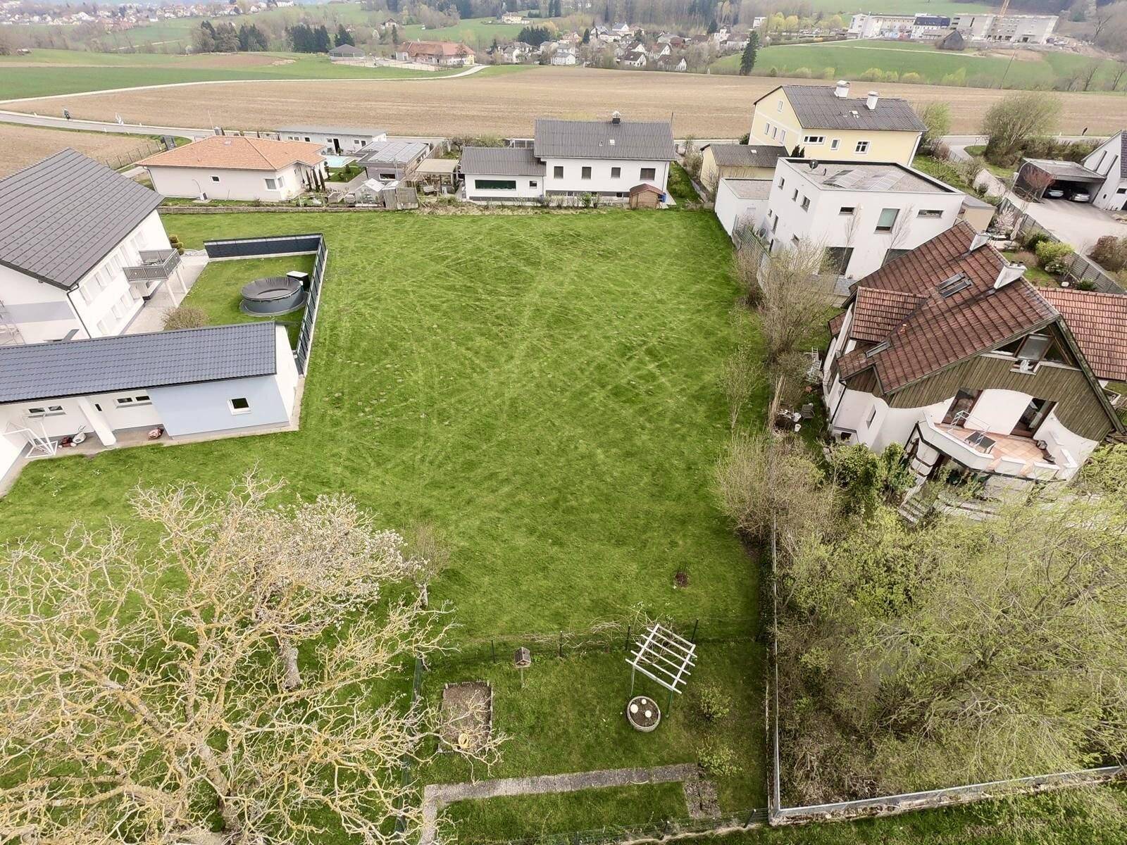 Vogelperspektive auf ein weitläufiges Grundstück mit Rasenfläche und angrenzenden Gebäuden.
