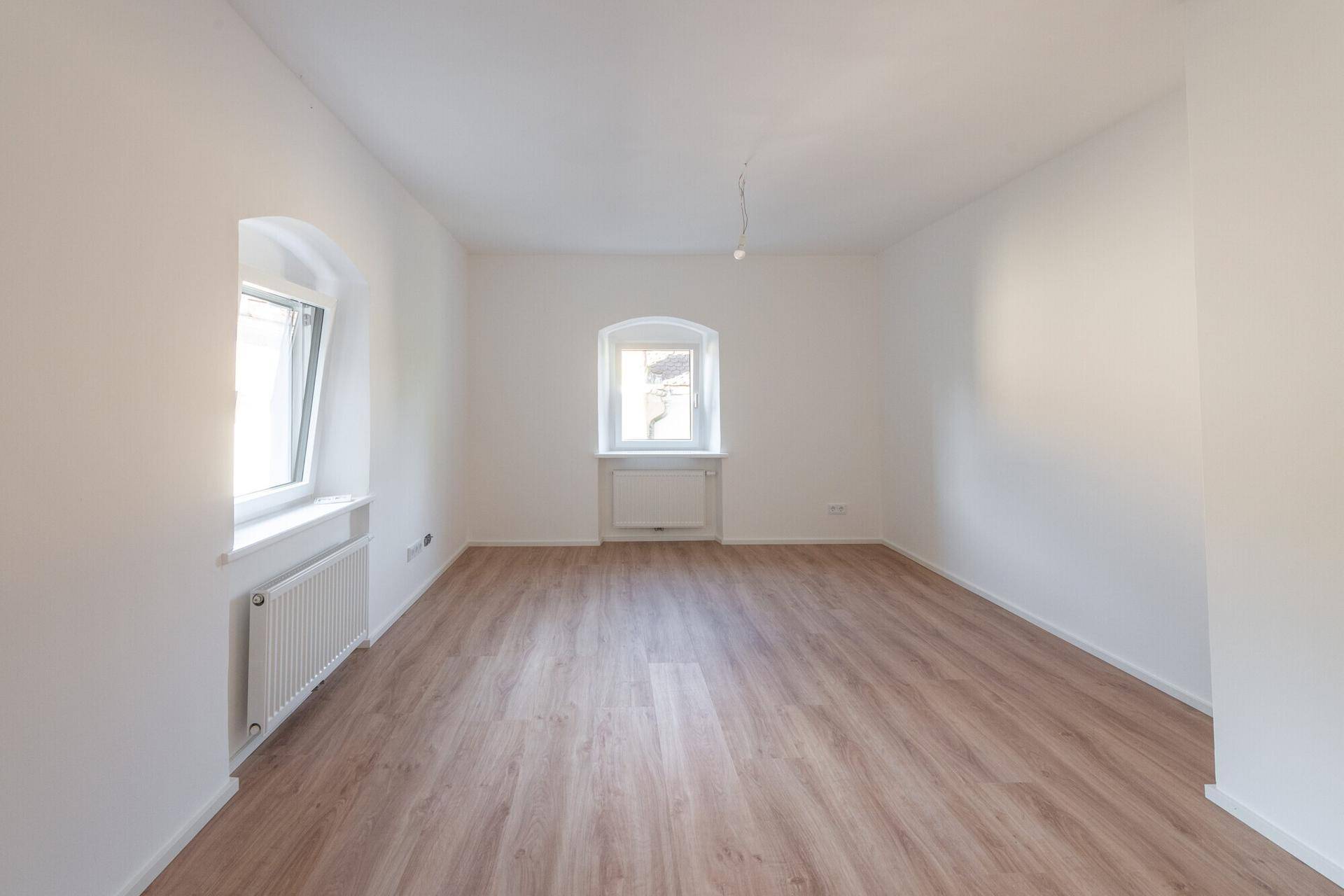 Geräumiger, heller Raum mit Laminatboden und weißen Wänden, ideal für individuelle Gestaltung.