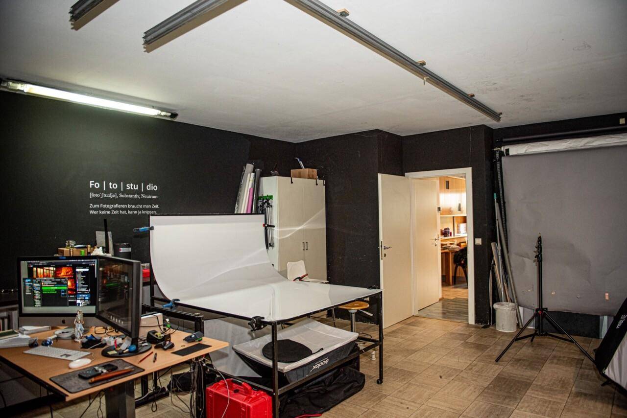 Professionelles Fotostudio mit Arbeitsplatz, Hintergrundsystem und Beleuchtung, bereit für kreative Projekte.