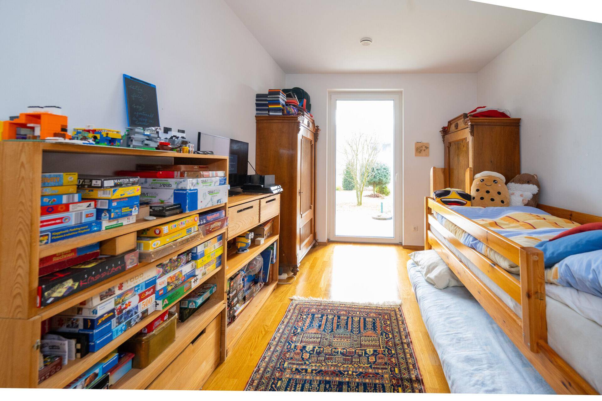 Helles Kinderzimmer mit Holzboden, Stauraum und direktem Zugang zum Garten.