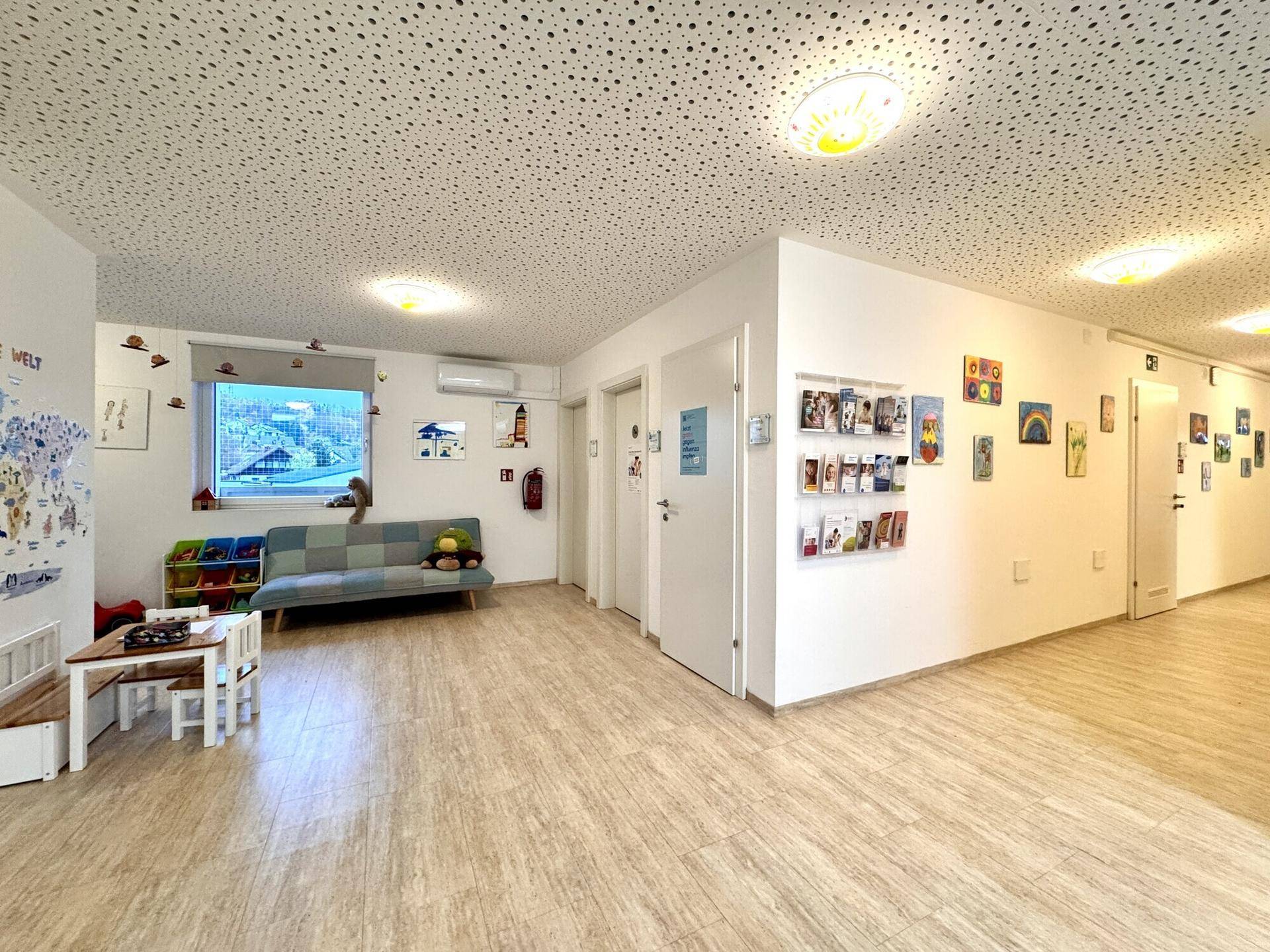 Heller Gemeinschaftsraum mit Kindermöbeln, Spielzeug und Bildern an den Wänden, ideal für Familien.