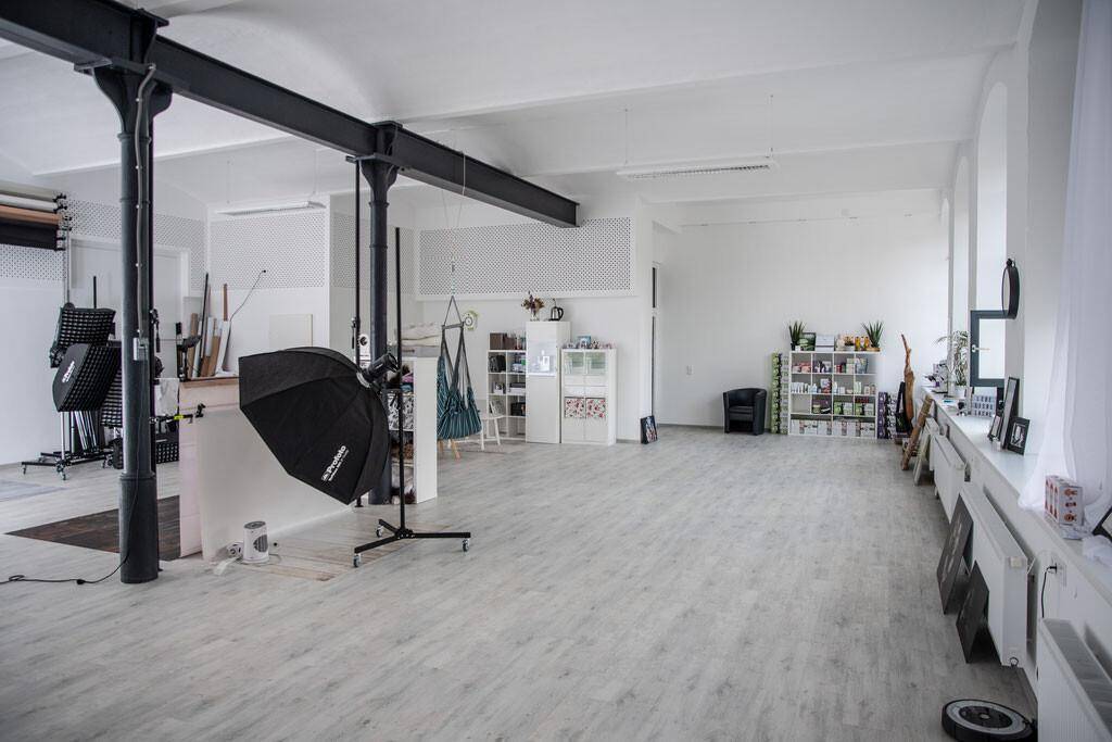 Weitläufiger, offener Raum mit hohen Decken und professioneller Fotoausrüstung, bereit für kreative Projekte.