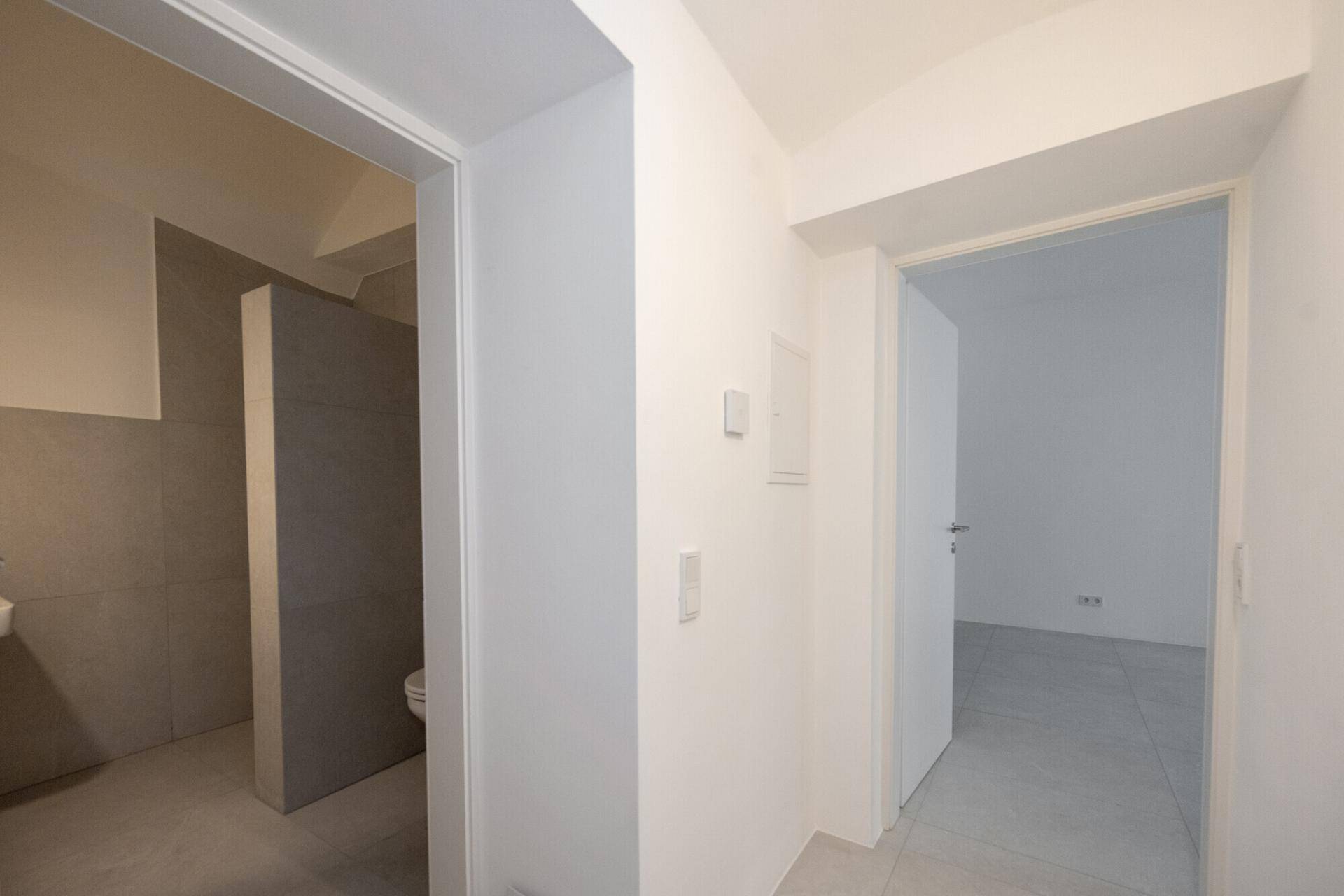 Heller Flur mit Zugang zu einem modernen Badezimmer und weiteren frisch renovierten Räumen.