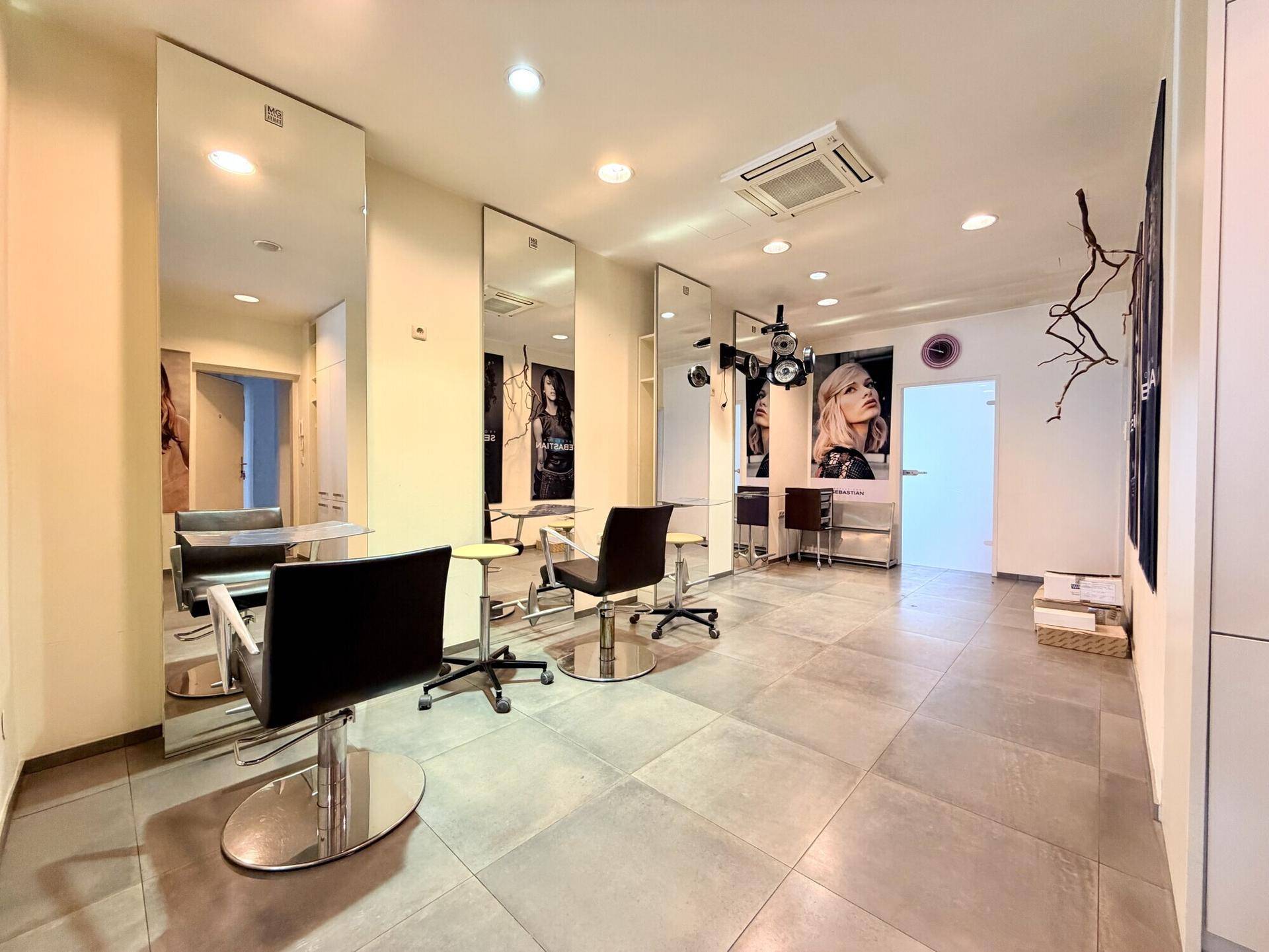 Moderner Friseursalon mit mehreren Frisierplätzen, großen Spiegeln und Klimaanlage.