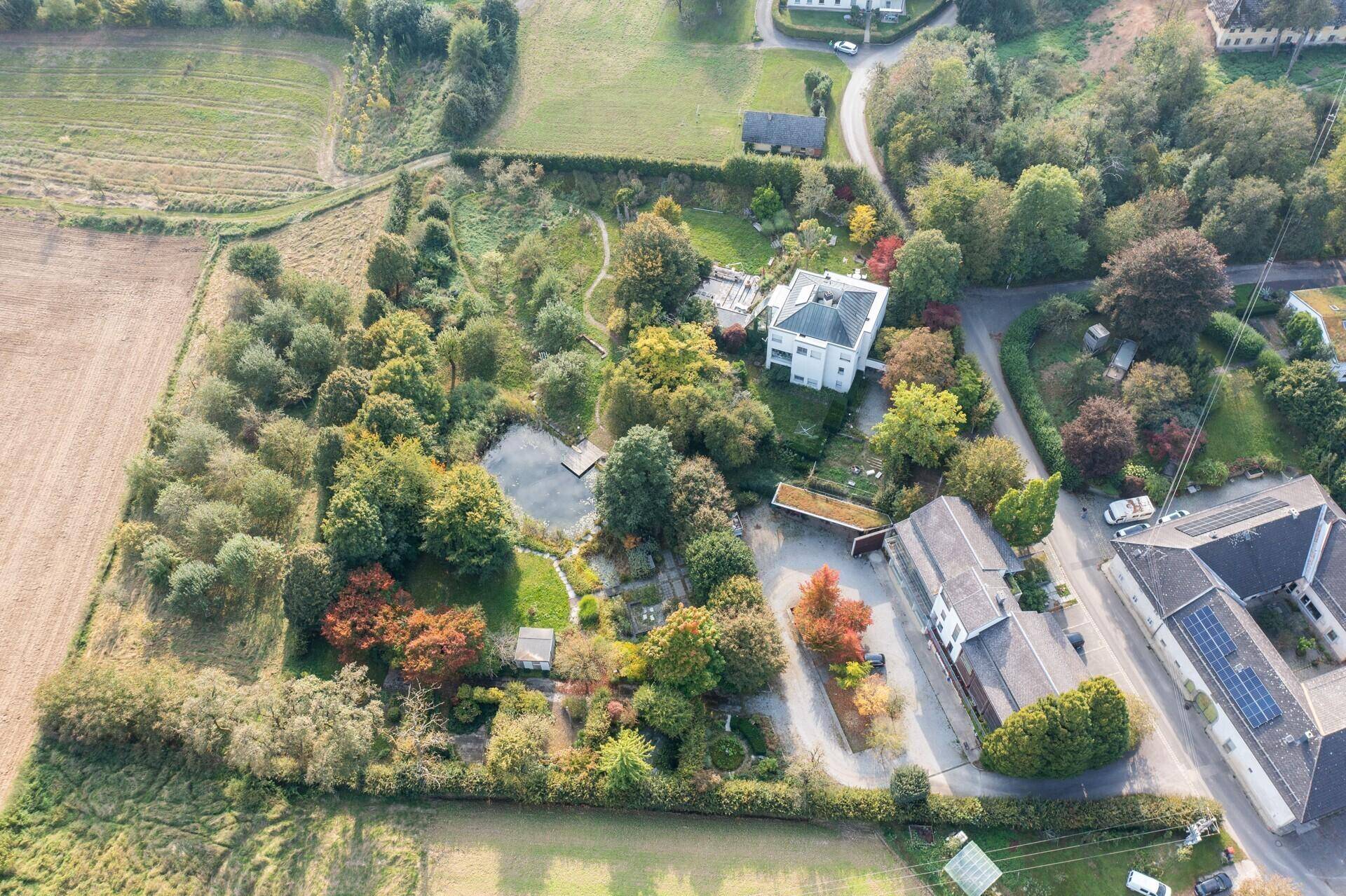 Panoramische Luftaufnahme des weitläufigen Anwesens mit Teich, Garten und angrenzenden Feldern.