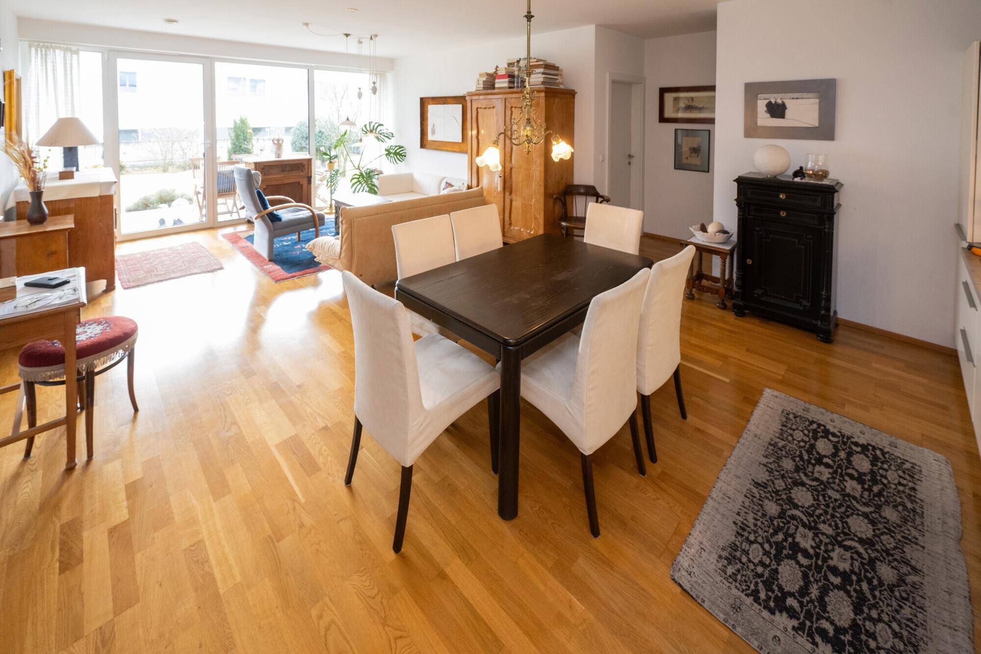 Offener Wohn- und Essbereich mit Holzboden, viel Tageslicht und Blick ins Grüne.