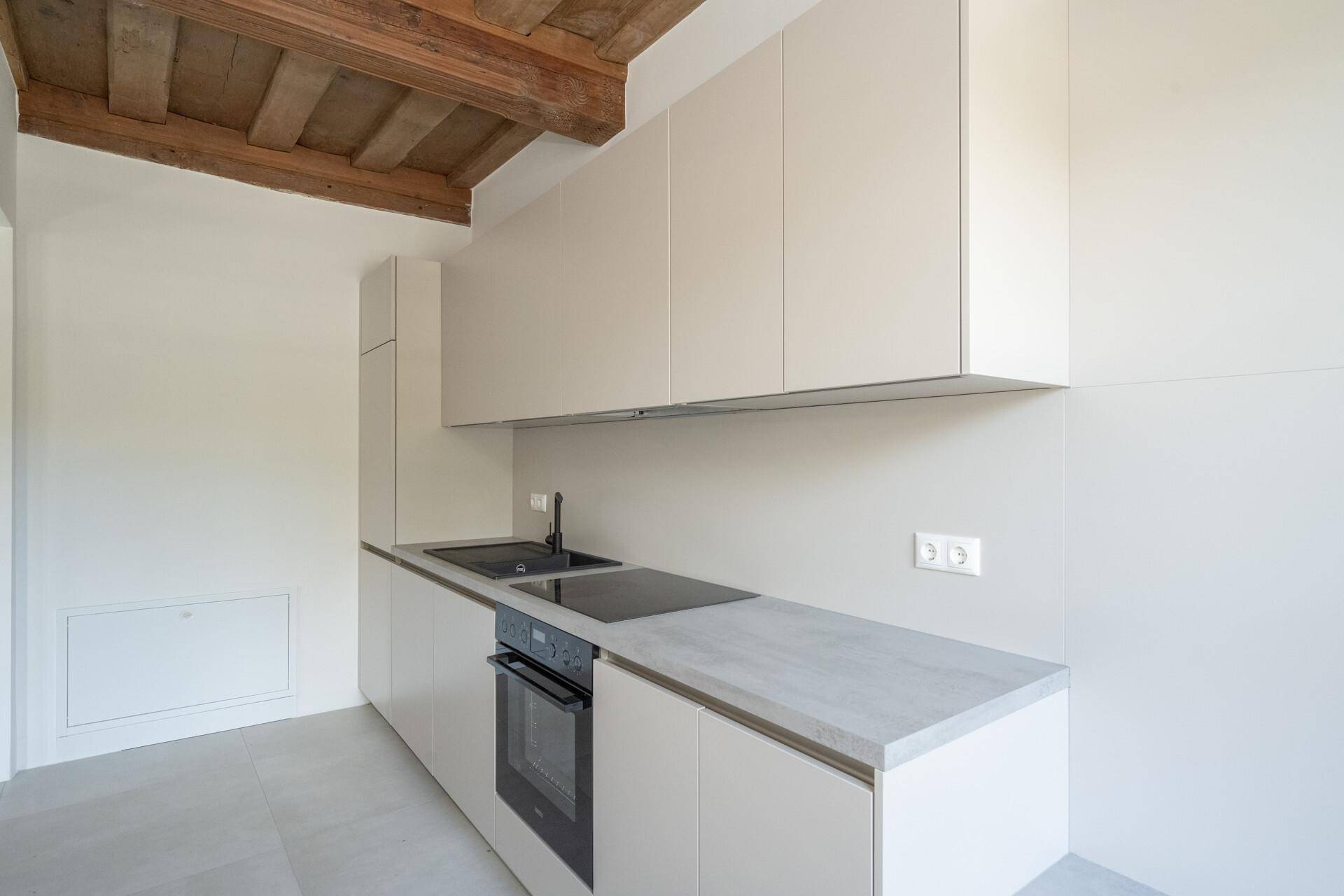 Schlichte, moderne Küche mit grauen Fronten, Induktionskochfeld und viel Stauraum.
