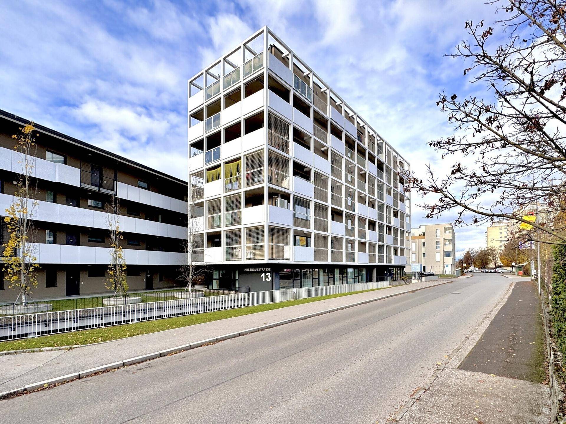 Zeitgenössisches Wohngebäude mit zahlreichen Balkonen und einer klaren architektonischen Struktur an einem sonnigen Tag.