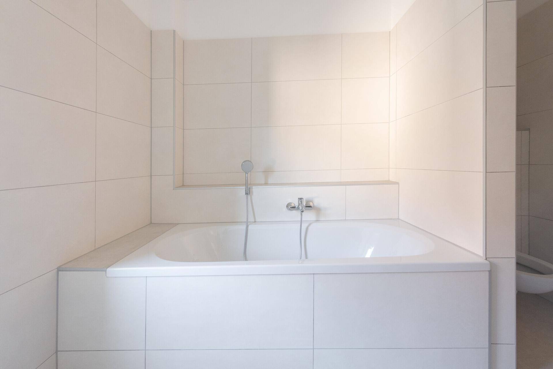 Eingebaute Badewanne in einem hell gefliesten Badezimmer mit moderner Armatur.