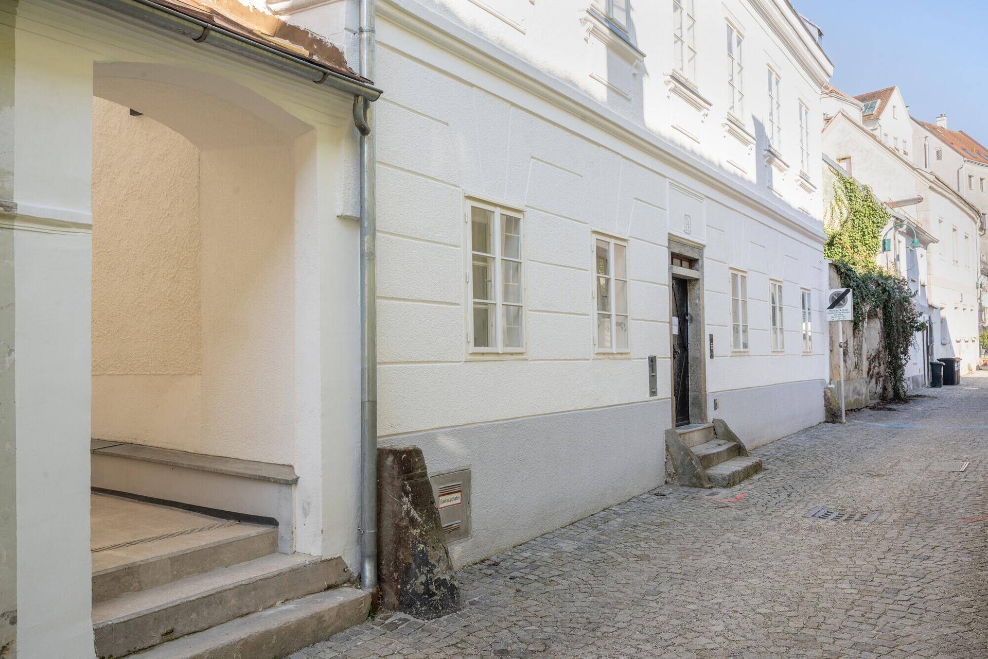 Ansicht eines historischen Gebäudes von der Gasse aus mit Eingangsbereich und Fenstern.