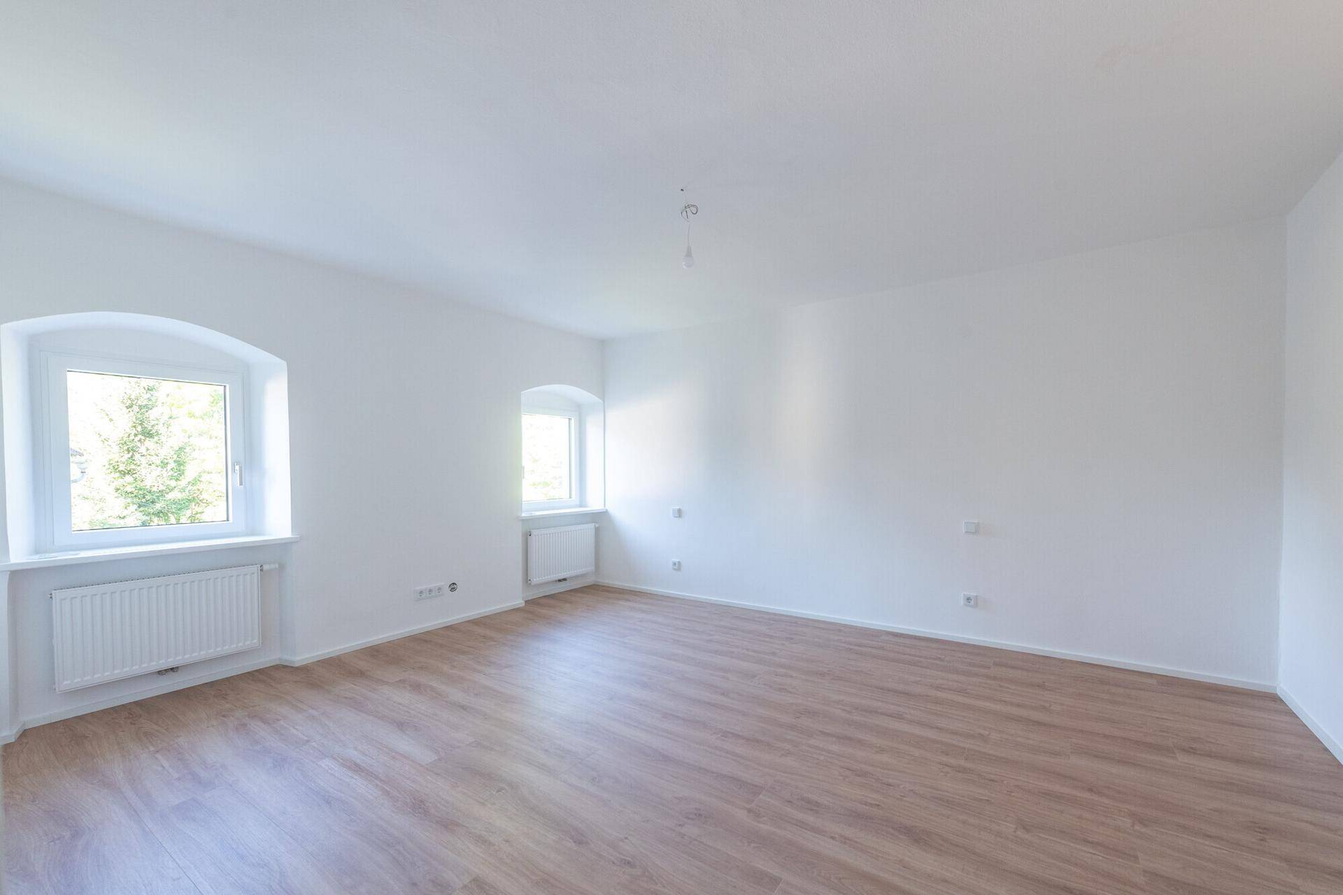 Heller Wohnraum mit Laminatboden und weißen Wänden, bietet vielseitige Nutzungsmöglichkeiten.