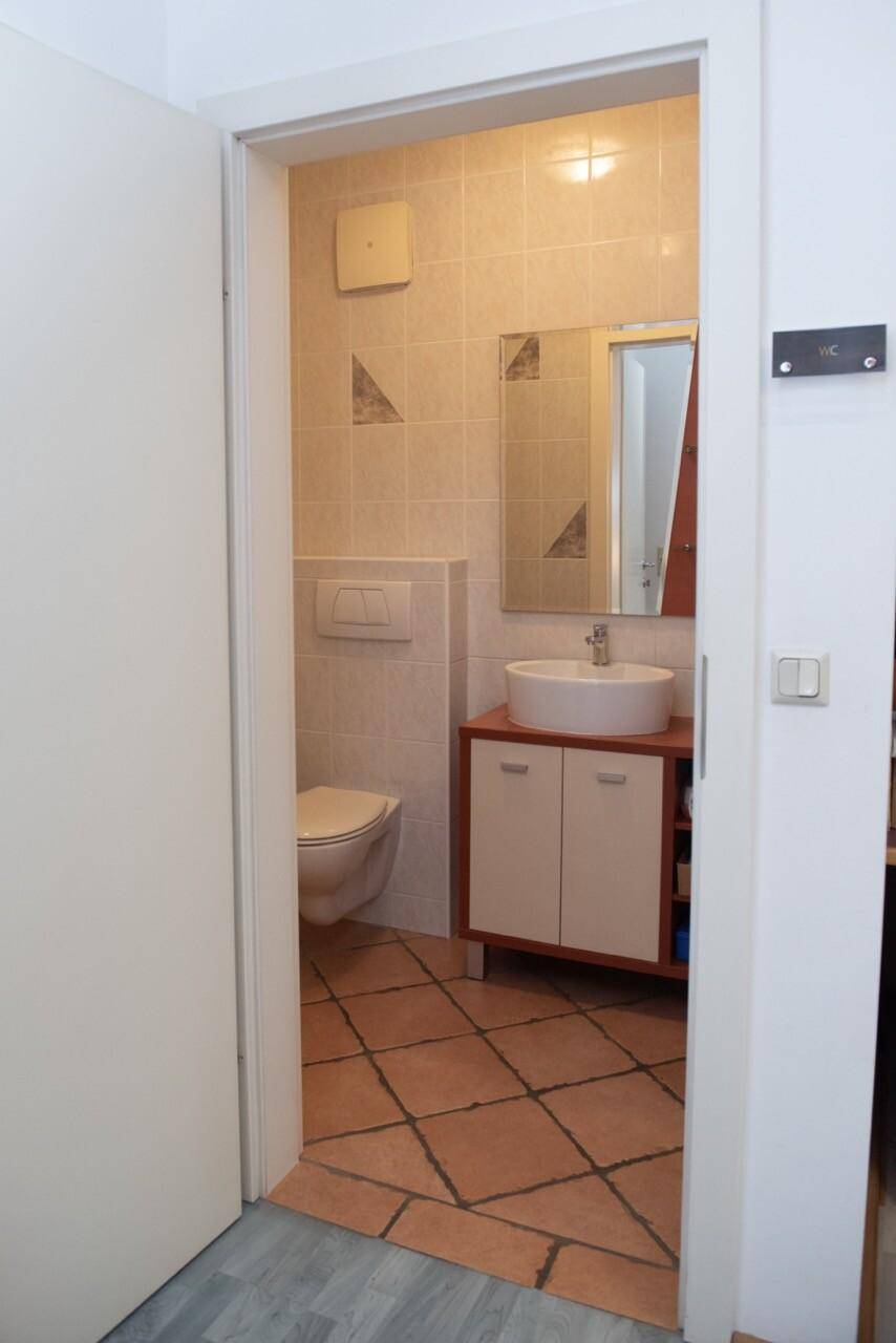 Kleines Badezimmer mit Waschbecken, Toilette und Terrakotta-Fliesenboden, traditionell und gepflegt.