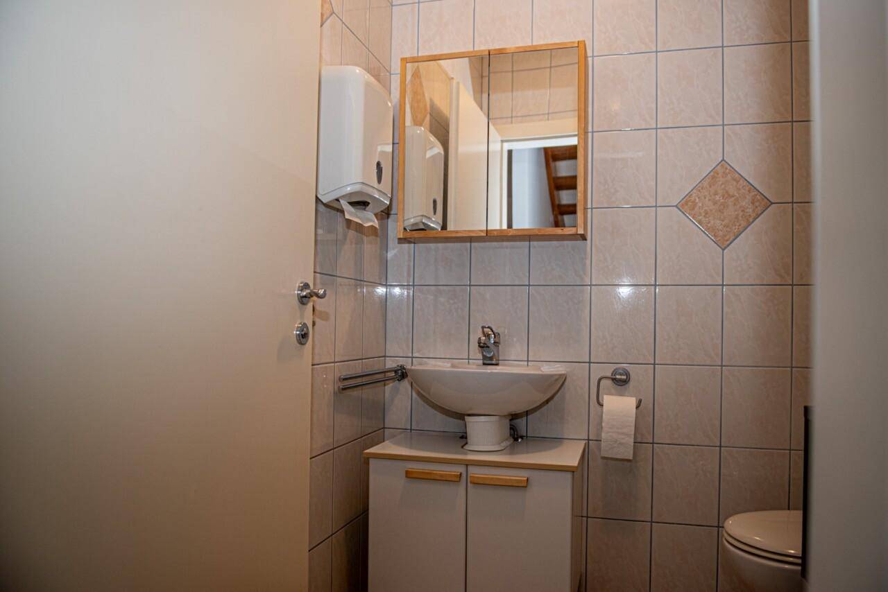 Kleines Badezimmer mit Waschbecken, Spiegel und Fliesen an den Wänden, sauber und funktional.