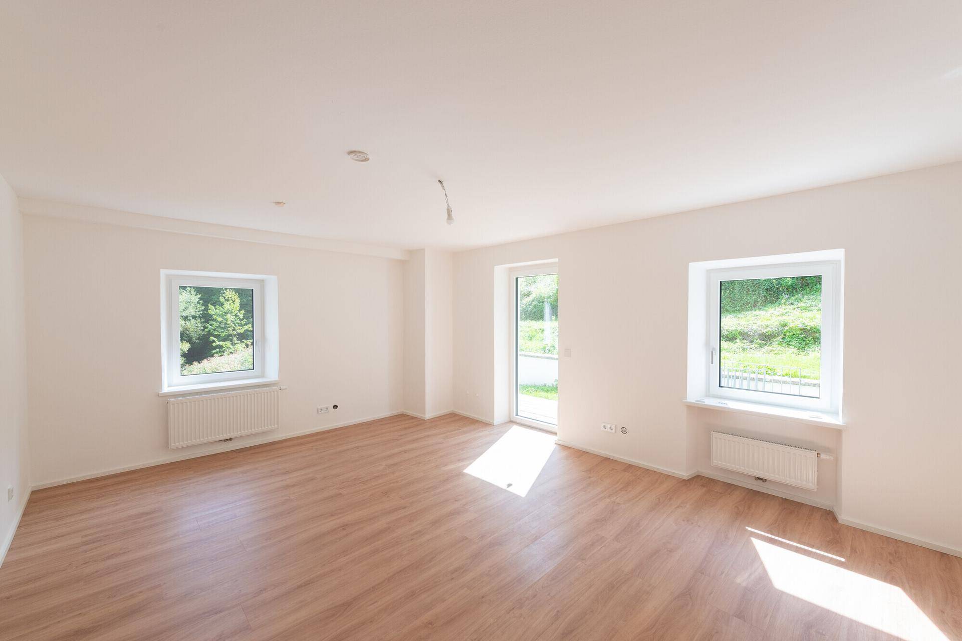 Geräumiger, heller Raum mit Laminatboden und Zugang zur Terrasse, ideal für Familien.