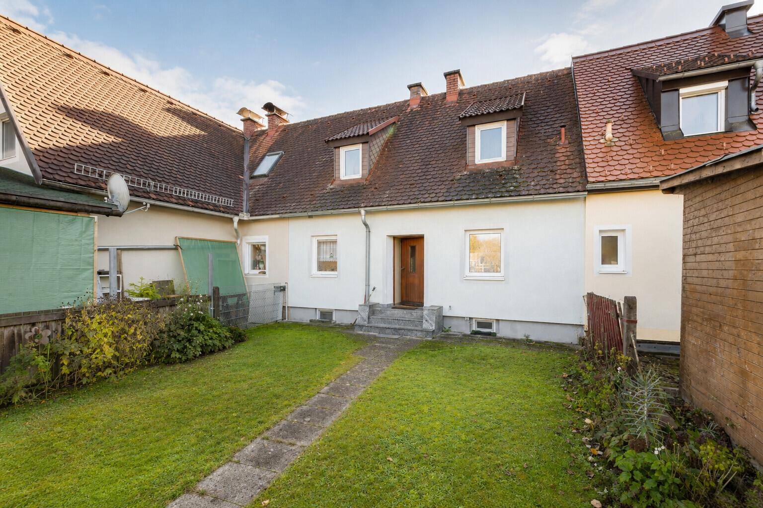 Rückansicht des Reihenhauses mit Garten, Rasenfläche und Zugang zum Haus.