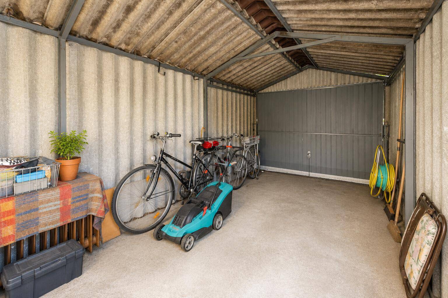 Einfache Garage oder Schuppen mit Fahrrädern und Gartengeräten.