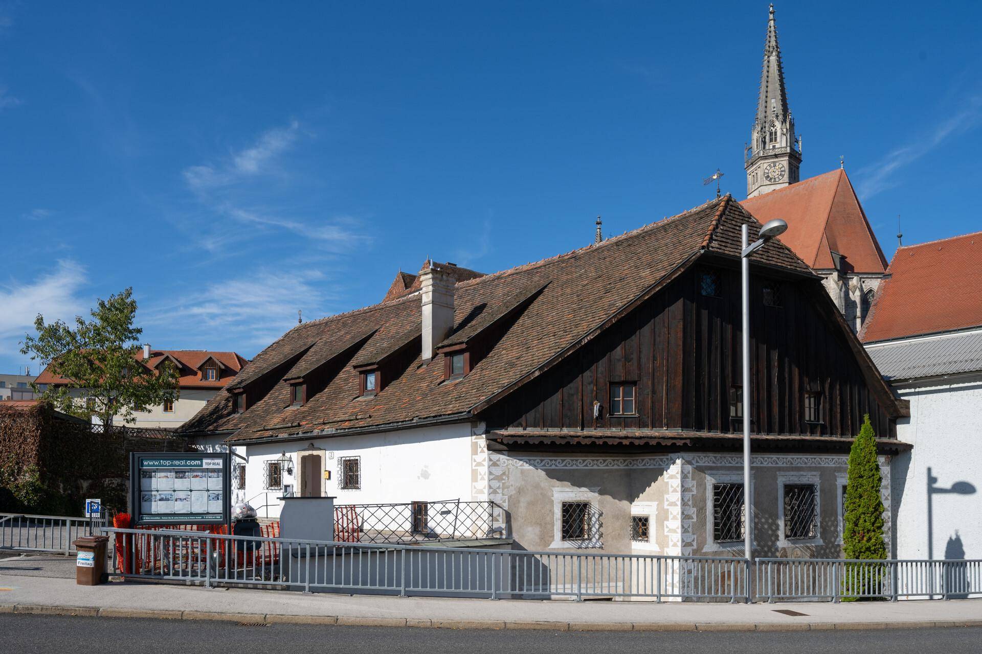 Historisches Gebäude mit Satteldach und Holzelementen in einer städtischen Umgebung.