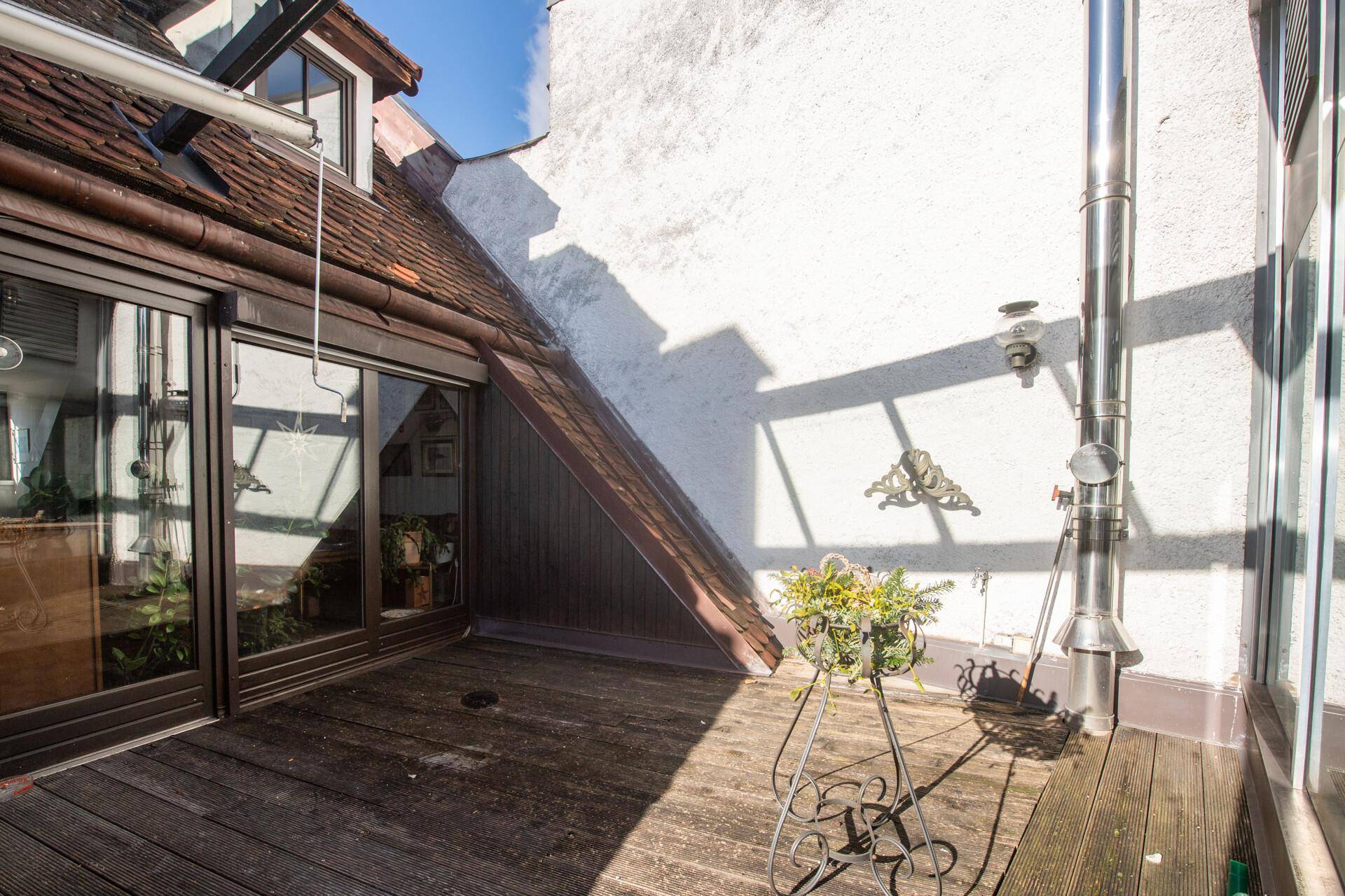 Holzterrasse mit Blick auf die Umgebung und viel Sonnenlicht.