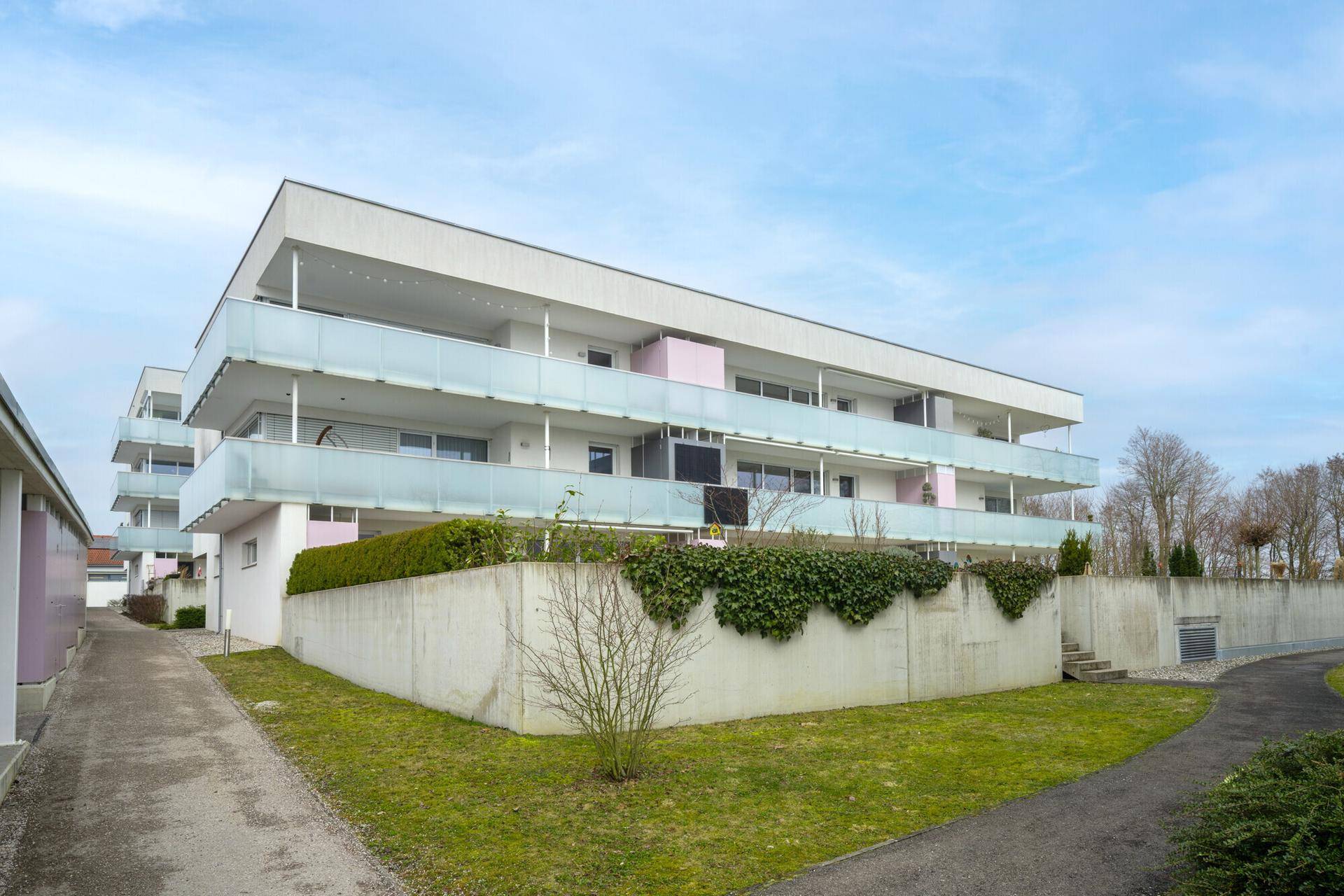 Modernes Wohngebäude mit mehreren Balkonen und einer gepflegten Außenanlage.