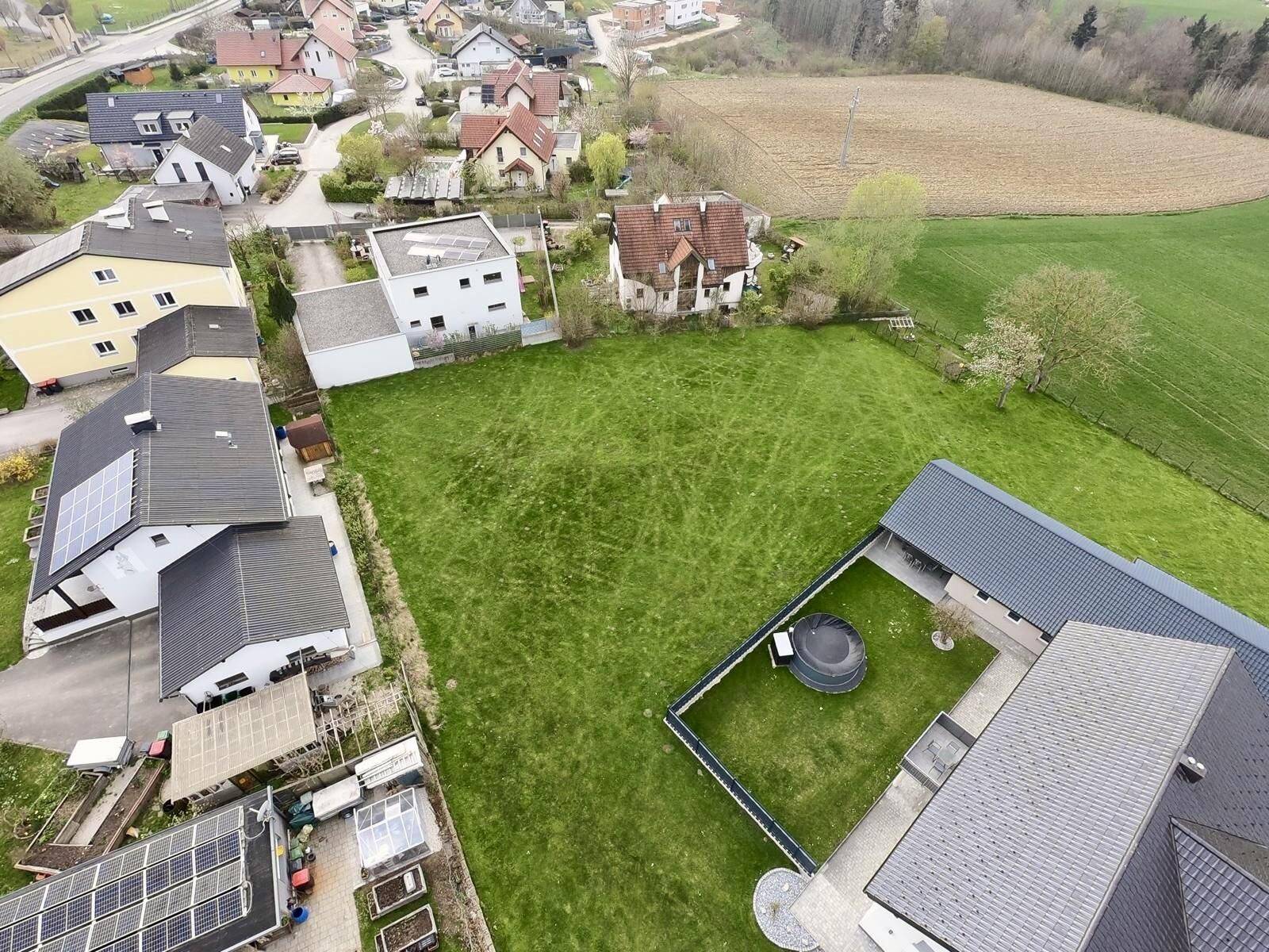 Luftaufnahme eines Wohngebiets mit mehreren Grundstücken und angrenzenden Feldern.