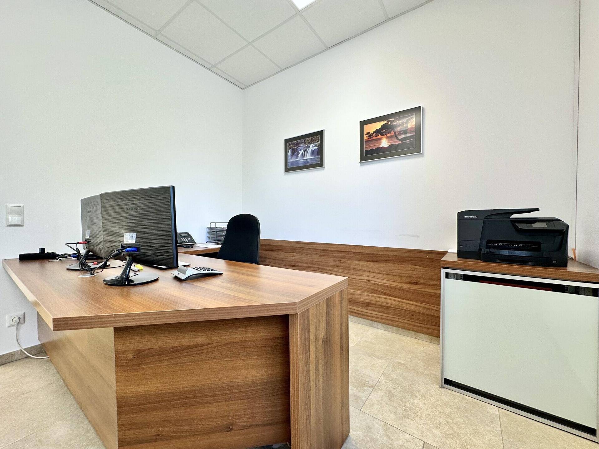 Modernes Büro mit großem Holzschreibtisch, Drucker und weißen Wänden.