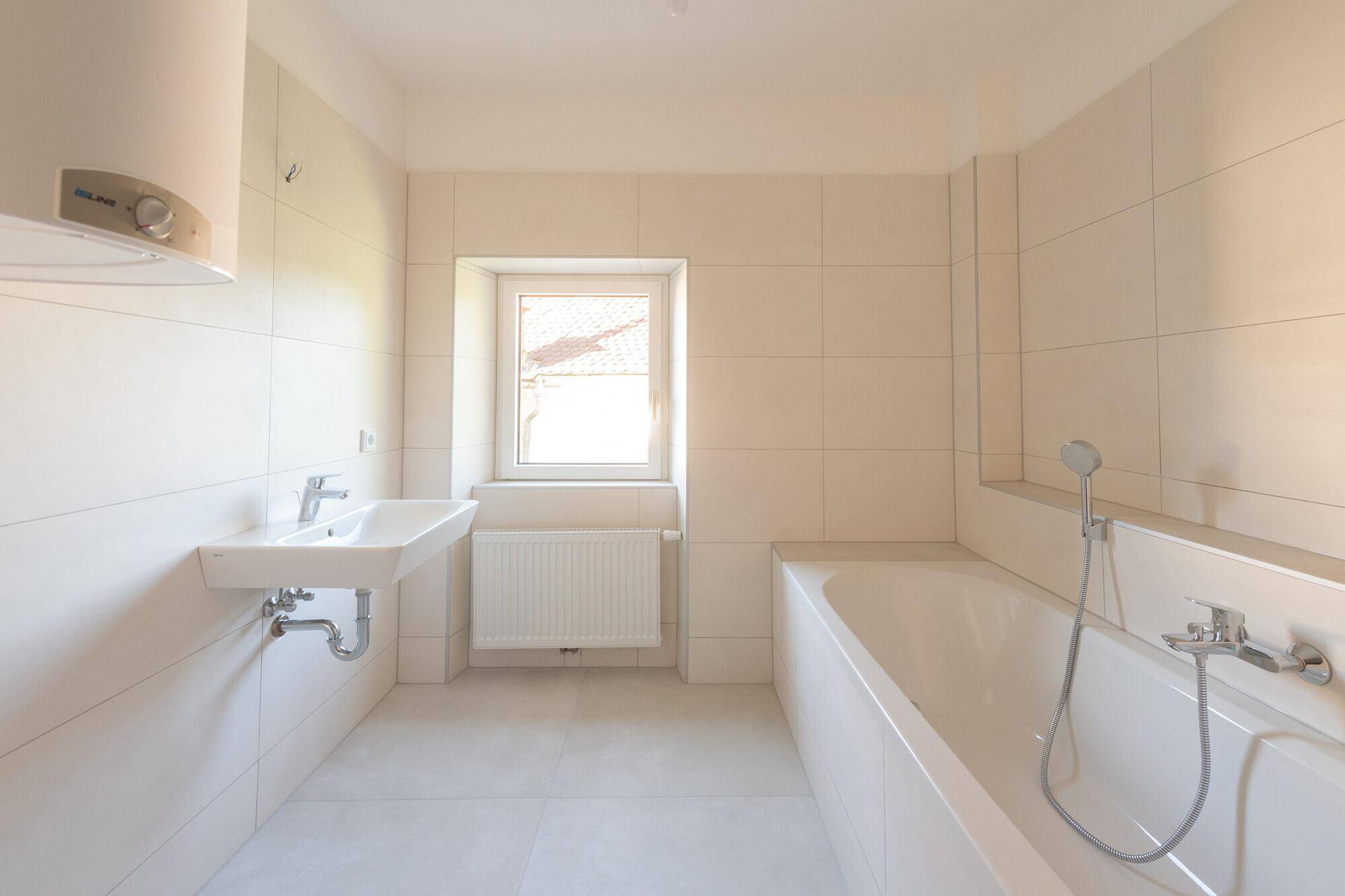 Modernes Badezimmer mit weißen Fliesen, Badewanne, Waschbecken und Fenster.