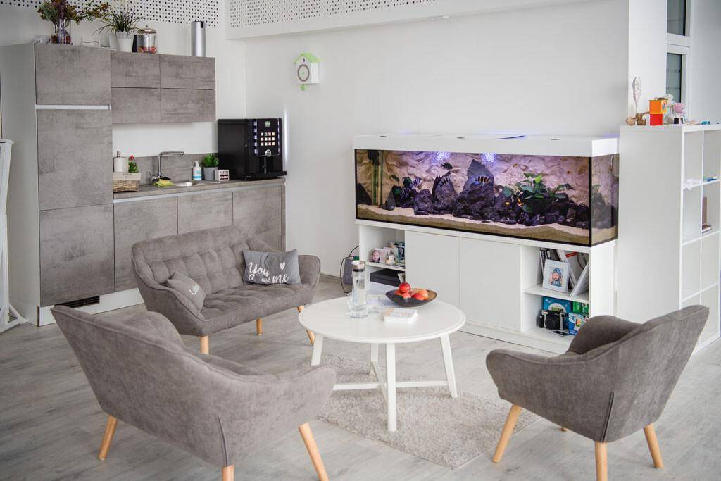 Gemütlicher Loungebereich mit moderner Küchenzeile, bequemen Sofas und einem großen Aquarium.
