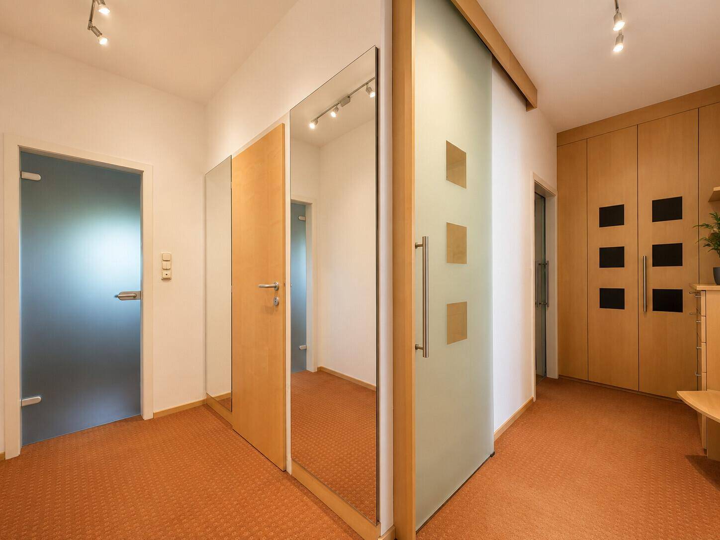 Geräumiger Flur mit Teppichboden, Spiegeltüren und praktischen Einbauschränken.