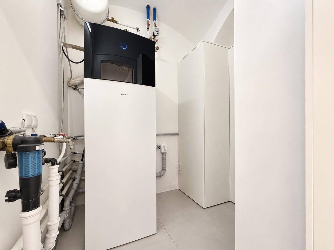 Technikraum mit moderner Wärmepumpe, Warmwasserbereiter und Installationen.