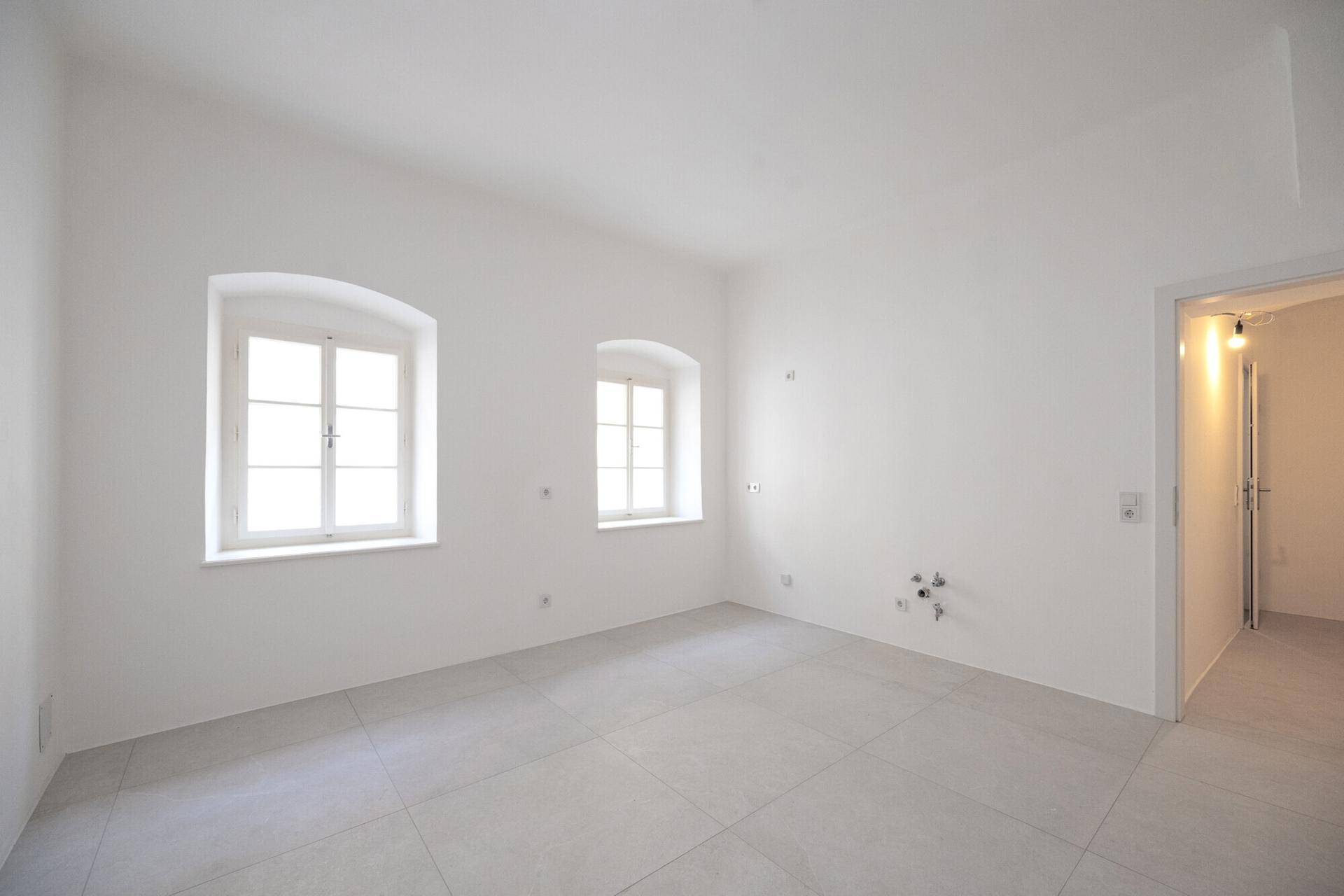 Heller Raum mit Fliesenboden und vorbereiteten Anschlüssen, ideal für ein modernes Badezimmer.